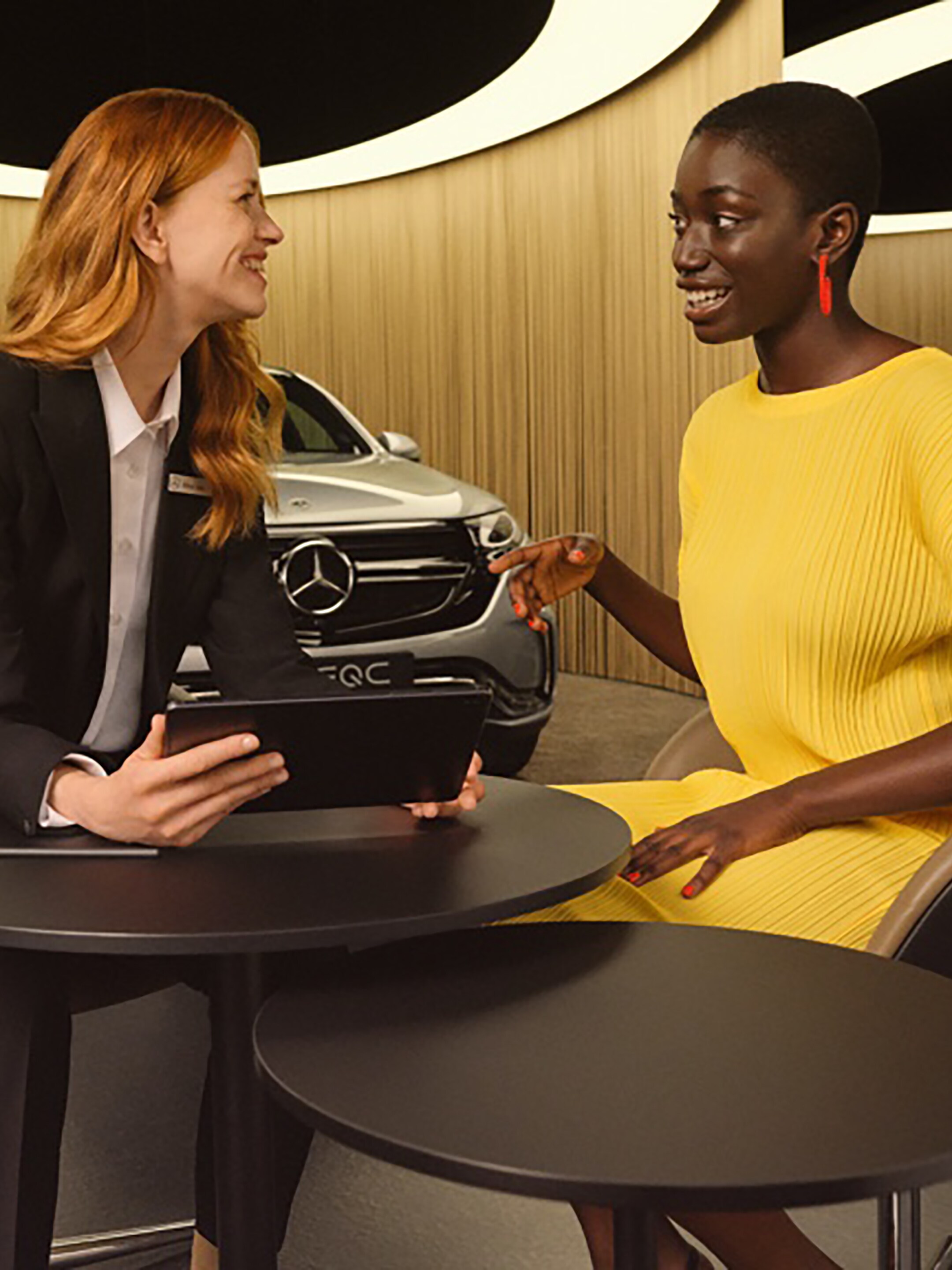 Dvě ženy se na tabletu informují o&nbsp;aplikacích Mercedes-Benz a&nbsp;digitálních doplňcích.