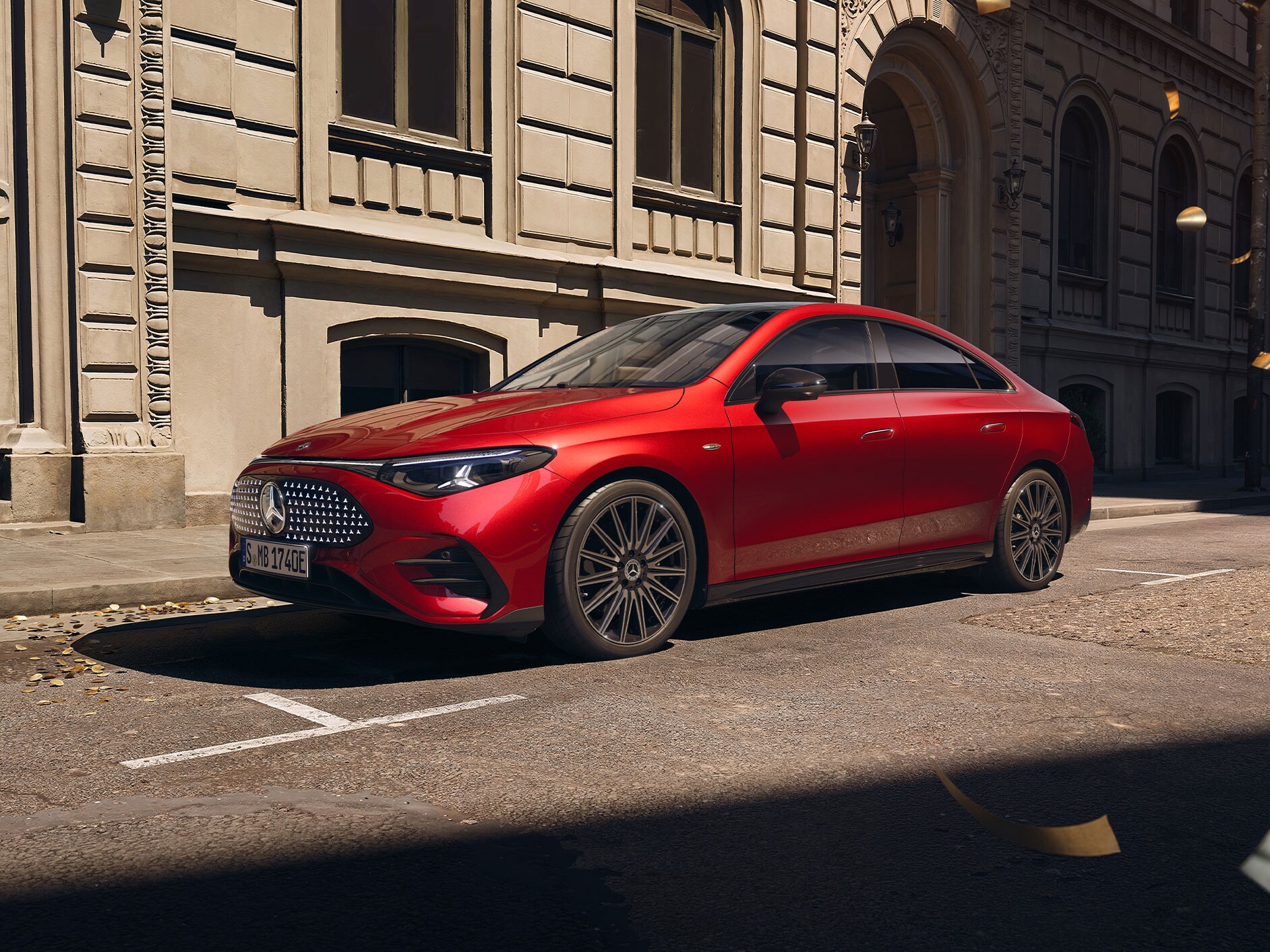 Červený Mercedes-Benz CLA, z levého boku. Jede po silnici, okolo létají zlaté konfety.