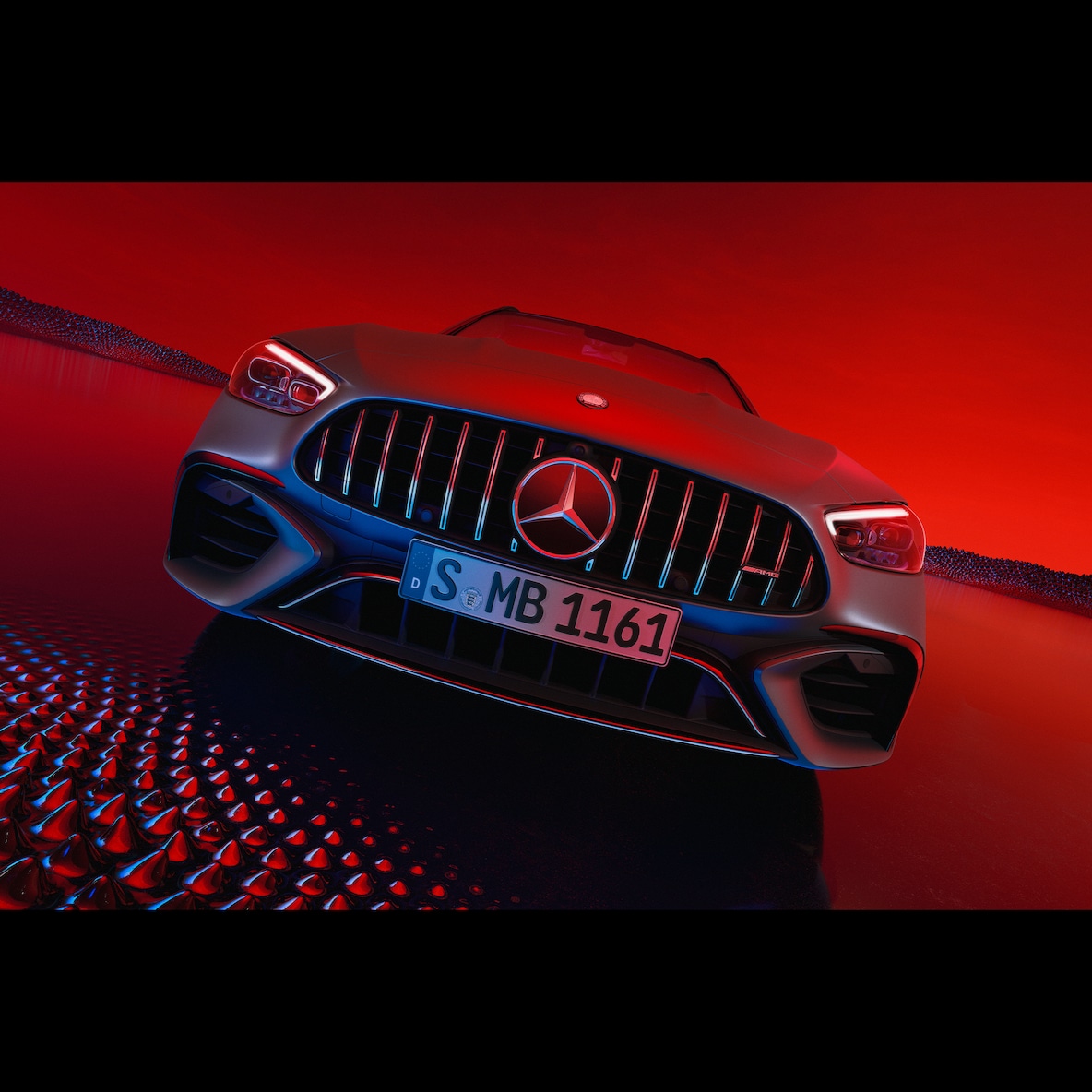 Mercedes-AMG C 63 S E PERFORMANCE při pohledu zepředu před červeným pozadím.