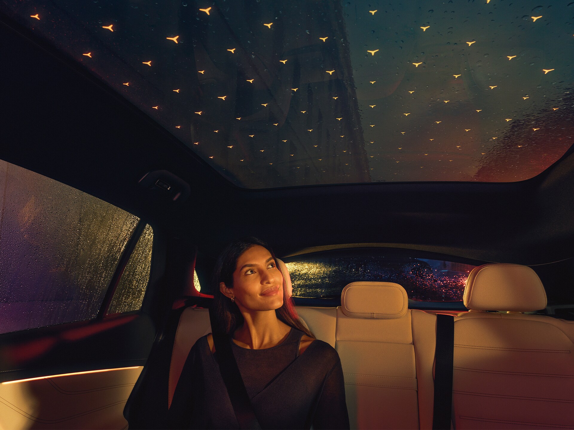 Cestující usazení ve vozidle Mercedes-Benz GLC s&nbsp;panoramatickým střešním oknem se zářícími světly v&nbsp;designu hvězd
