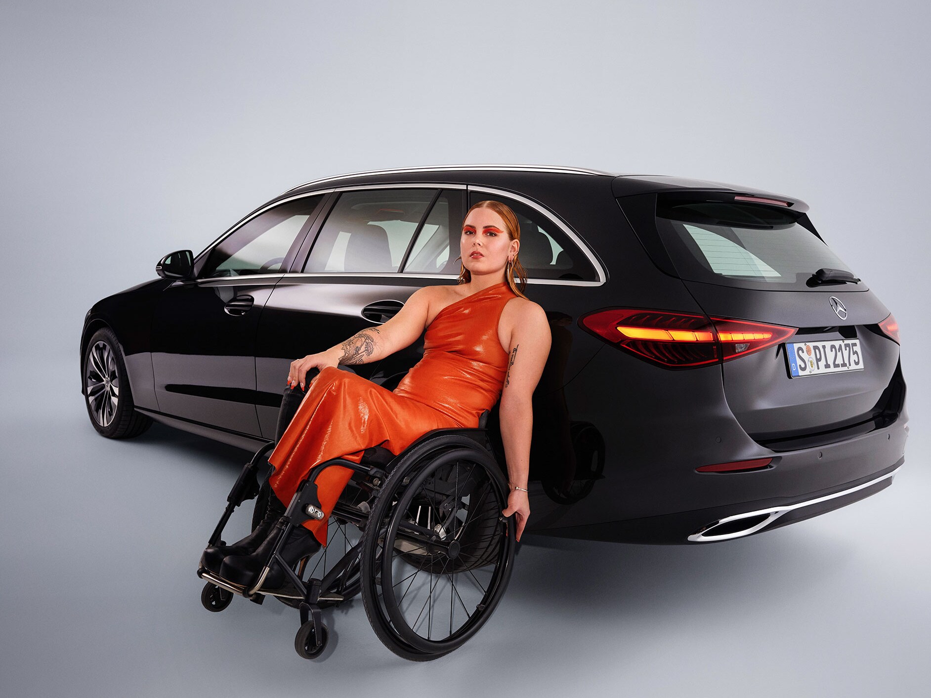 Vozidlo vhodné pro tělesně postižené - model Třídy C v šikmém pohledu zezadu a žena na invalidním vozíku.