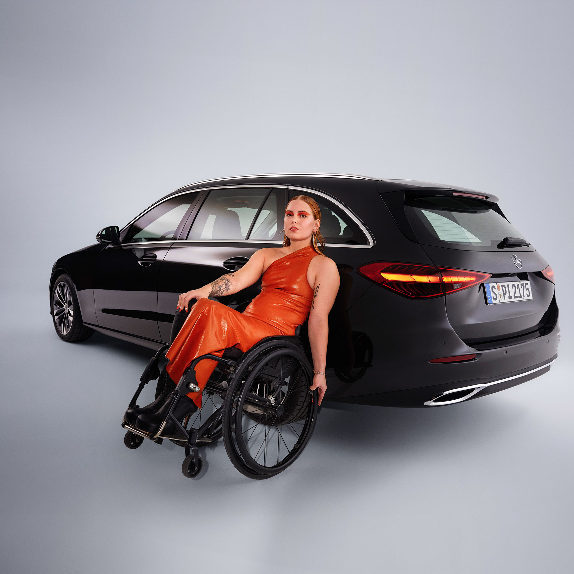 Kvalita | Jízdní pomocné prostředky | Mercedes-Benz Vozidlo vhodné pro tělesně postižené - model Třídy C v šikmém pohledu zezadu a žena na invalidním vozíku.