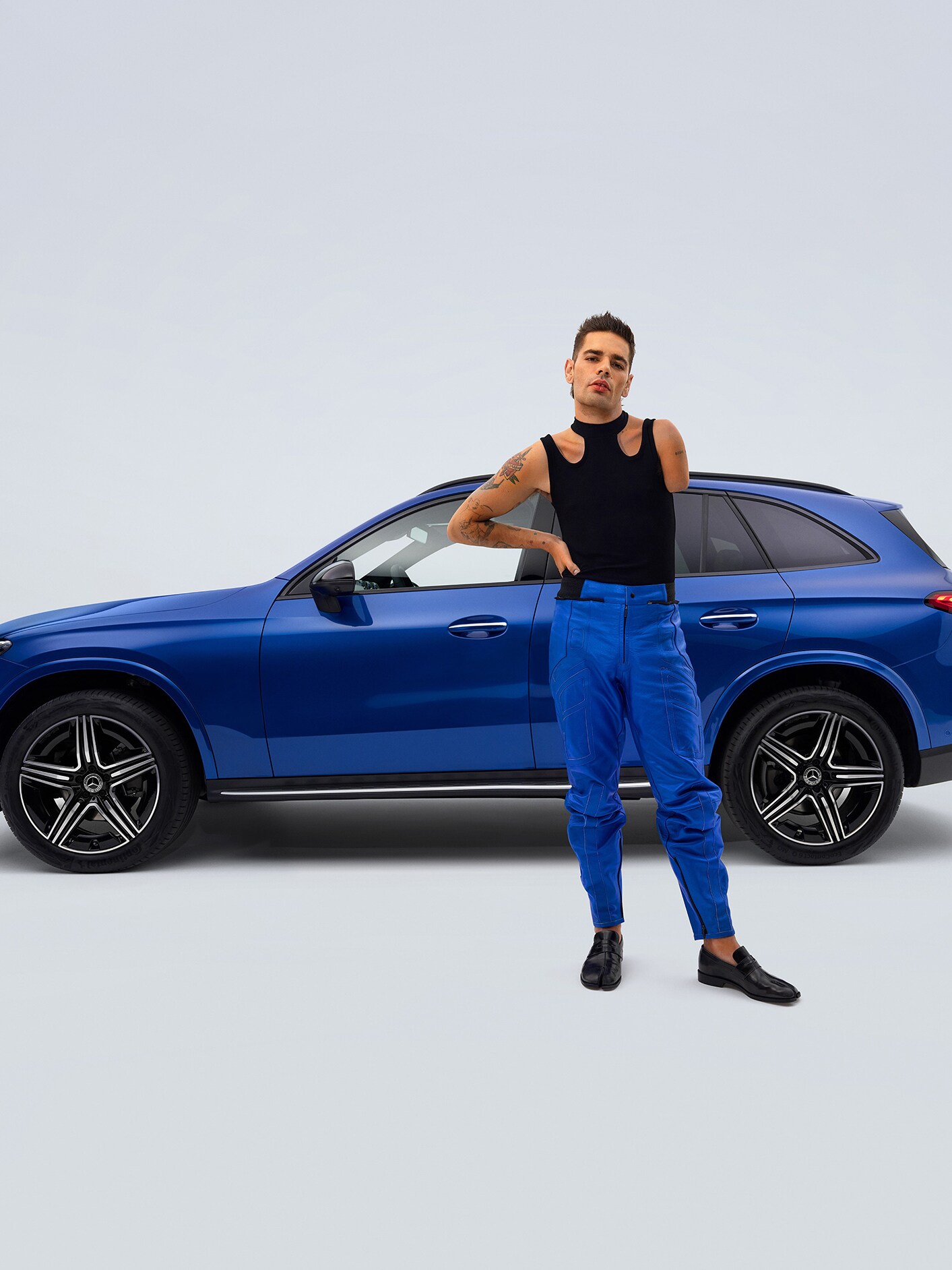 Pohled z&nbsp;boku na přestavěné vozidlo Mercedes-Benz GLC SUV vhodné pro invalidy a&nbsp;muže v&nbsp;popředí s&nbsp;amputovanou paží.