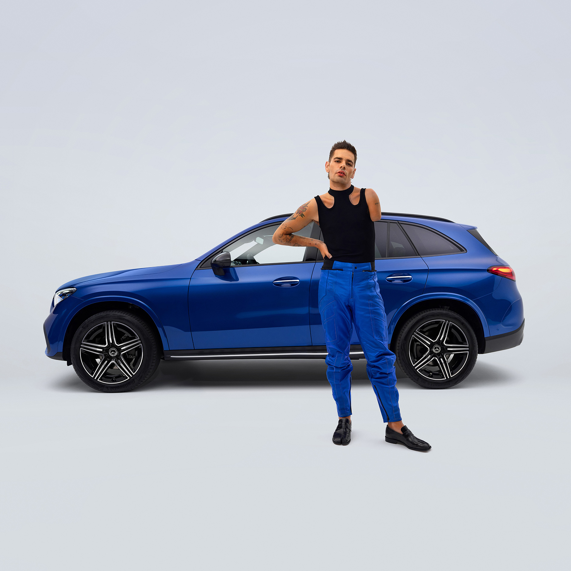 Pomocné prostředky pro řízení a ovládání | Pomůcky pro jízdu | Mercedes-Benz Pohled z boku na přestavěné vozidlo Mercedes-Benz GLC SUV vhodné pro invalidy a muže v popředí s amputovanou paží.