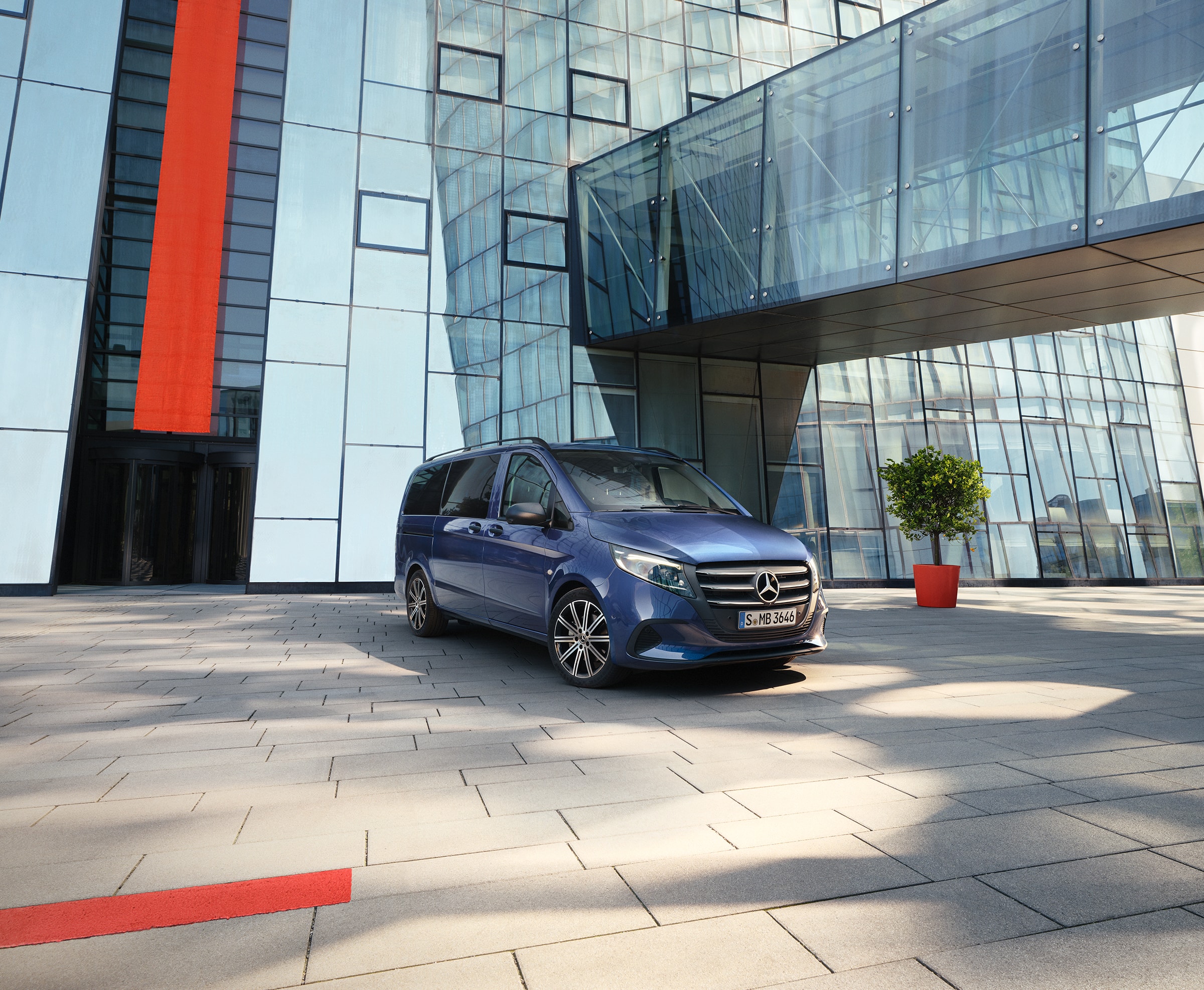 Vito Tourer | Modely dodávkových vozidel a cestovních automobilů | Dodávková vozidla Mercedes-Benz Mercedes-Benz Vito Tourer s posuvnými dveřmi před moderní budovou.