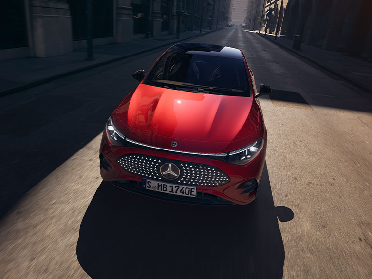 Úvěrové financovaní Agility pro Váš Mercedes-Benz Červený Mercedes-Benz CLA vyfocený zepředu, jedoucí po silnici. Svítí slunce.