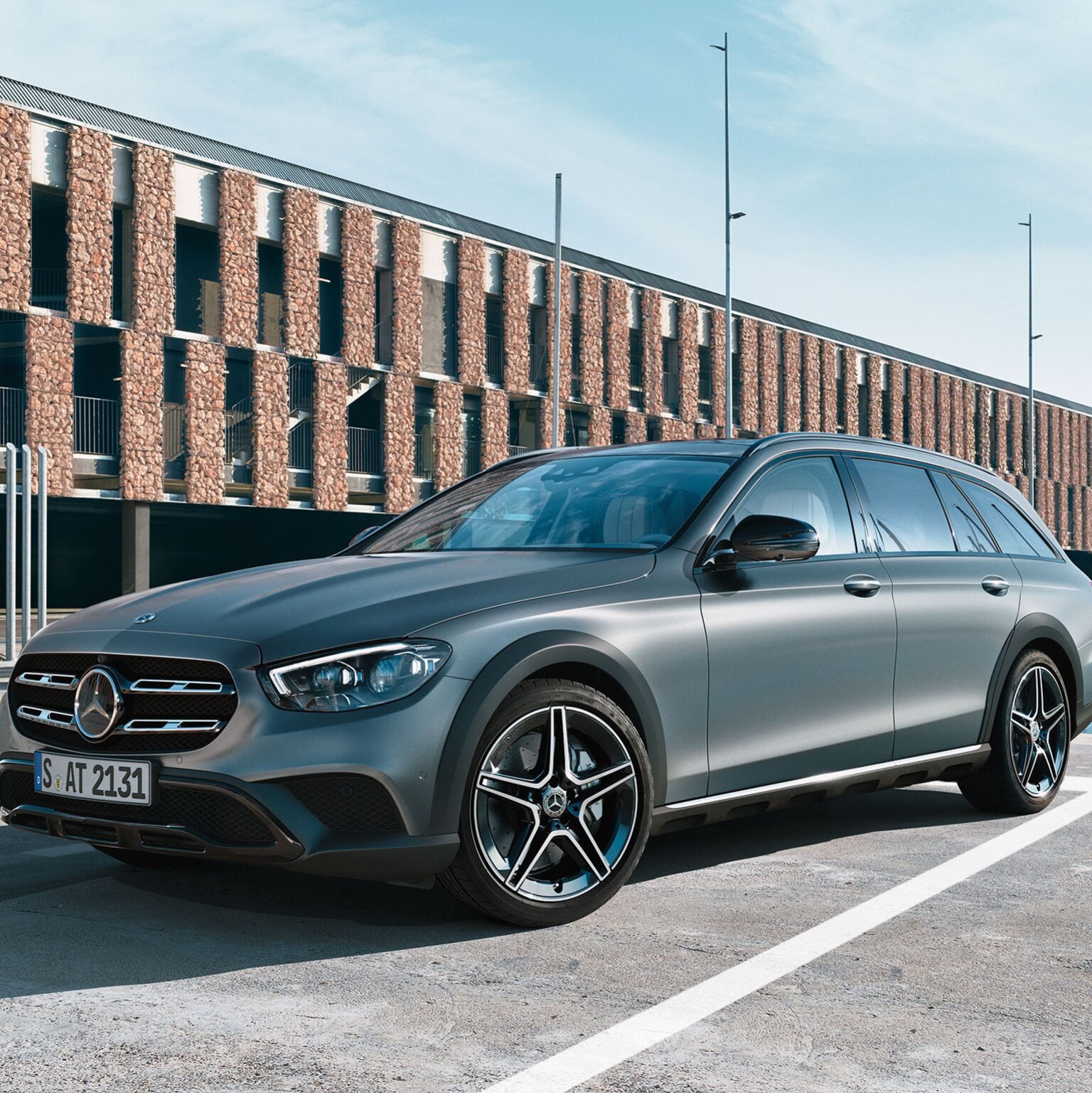 Vůz Mercedes-Benz stojí čelem k objektivu na nábřeží na parkovacím místě. Na pozadí jsou vidět zaparkované lodě.