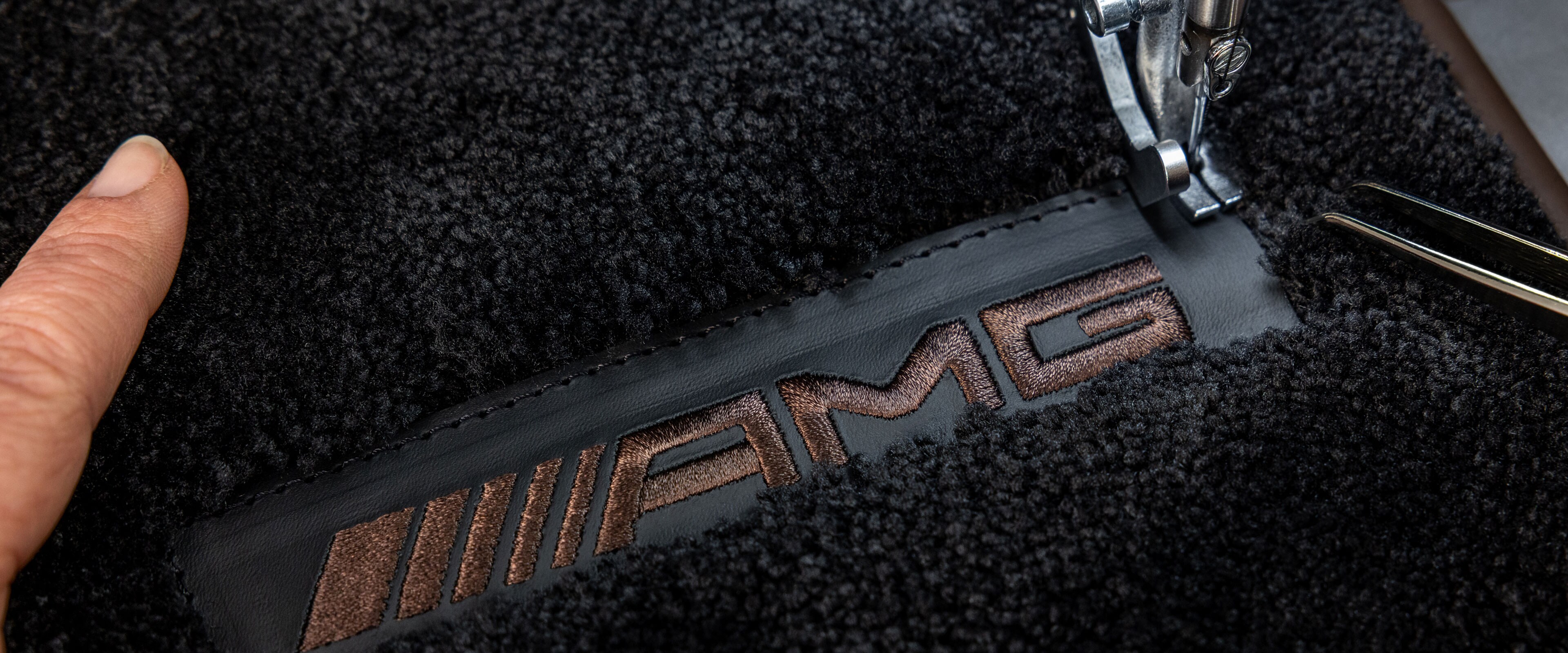 Nápis MANUFAKTUR na tmavém povrchu ve vozidle Mercedes-AMG.