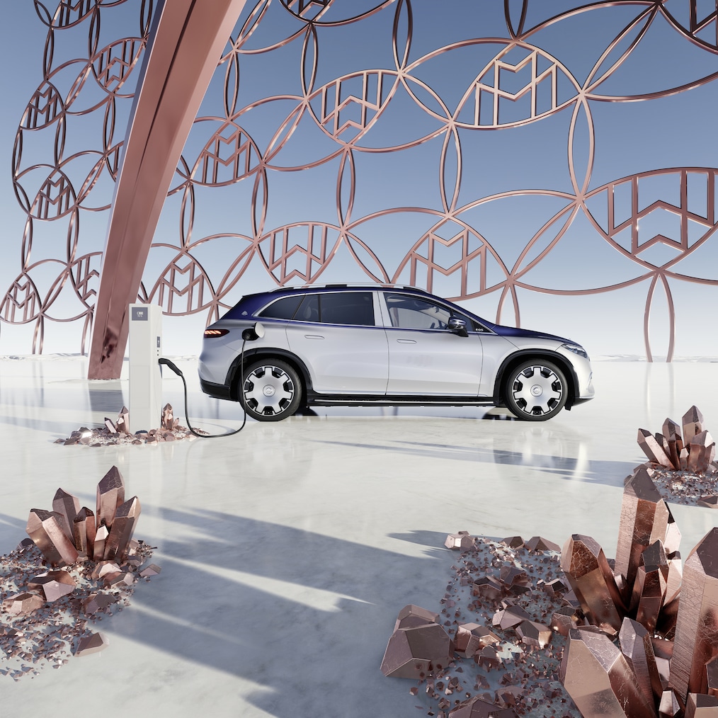 Pohled z&nbsp;boku na Mercedes-Maybach EQS SUV na nabíjecí stanici s&nbsp;logem značky Maybach v&nbsp;pozadí.