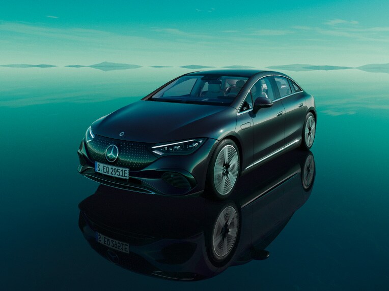 Plně elektrické EQE od Mercedes-Benz stojící v zeleném světě EQ se zrcadlící se podlahovou plochou.