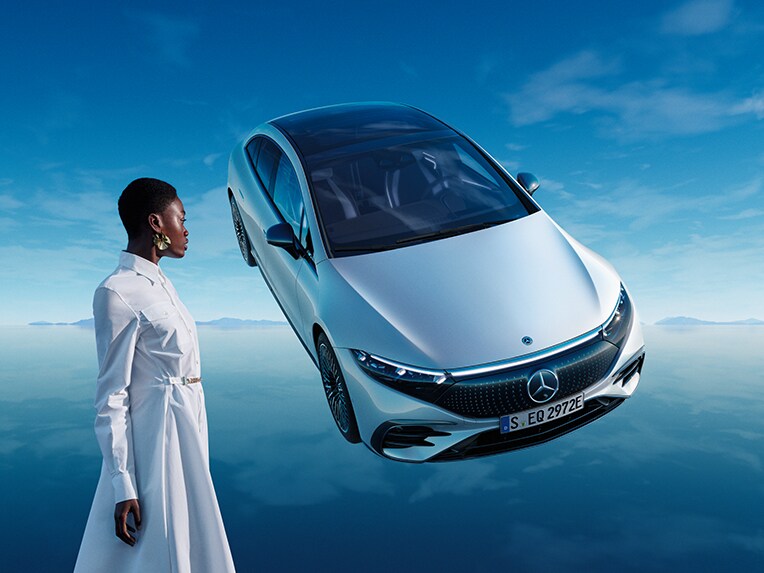 Plně elektrické EQS od Mercedes-Benz stojící v modrém světě EQ se zrcadlící se podlahovou plochou.