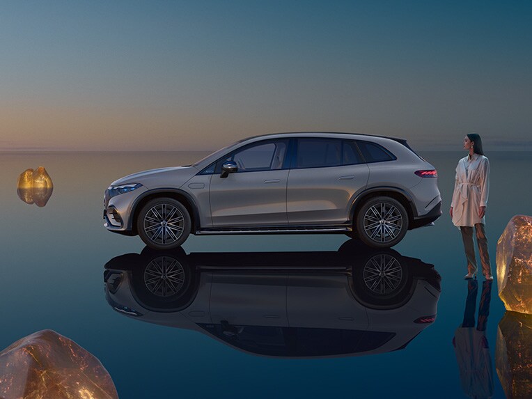 Plně elektrické EQS SUV od Mercedes-Benz stojící ve svém světě EQS SUV se zrcadlící se podlahovou plochou.
