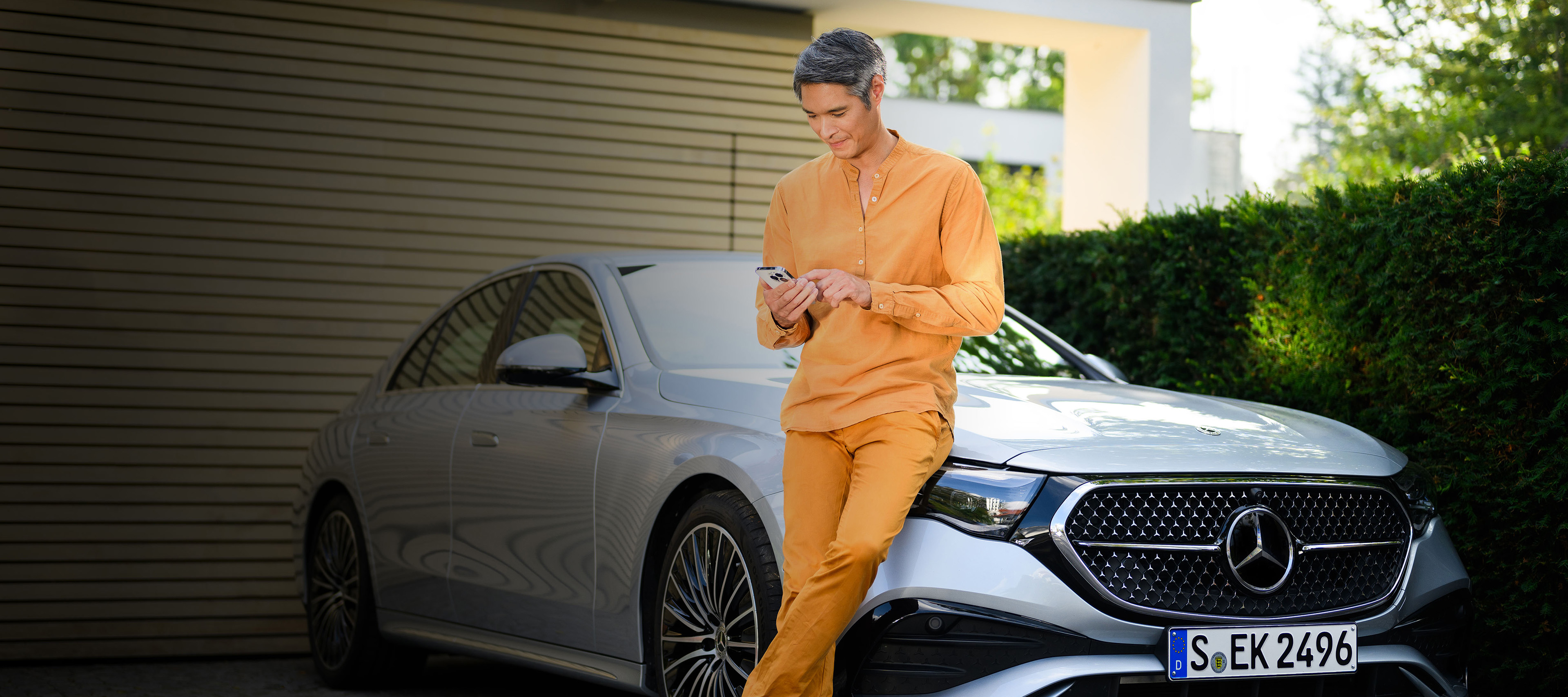 Akční nabídky | Finanční služby | Mercedes-Benz Osoba opřená o vozidlo Mercedes-Benz s mobilním telefonem.