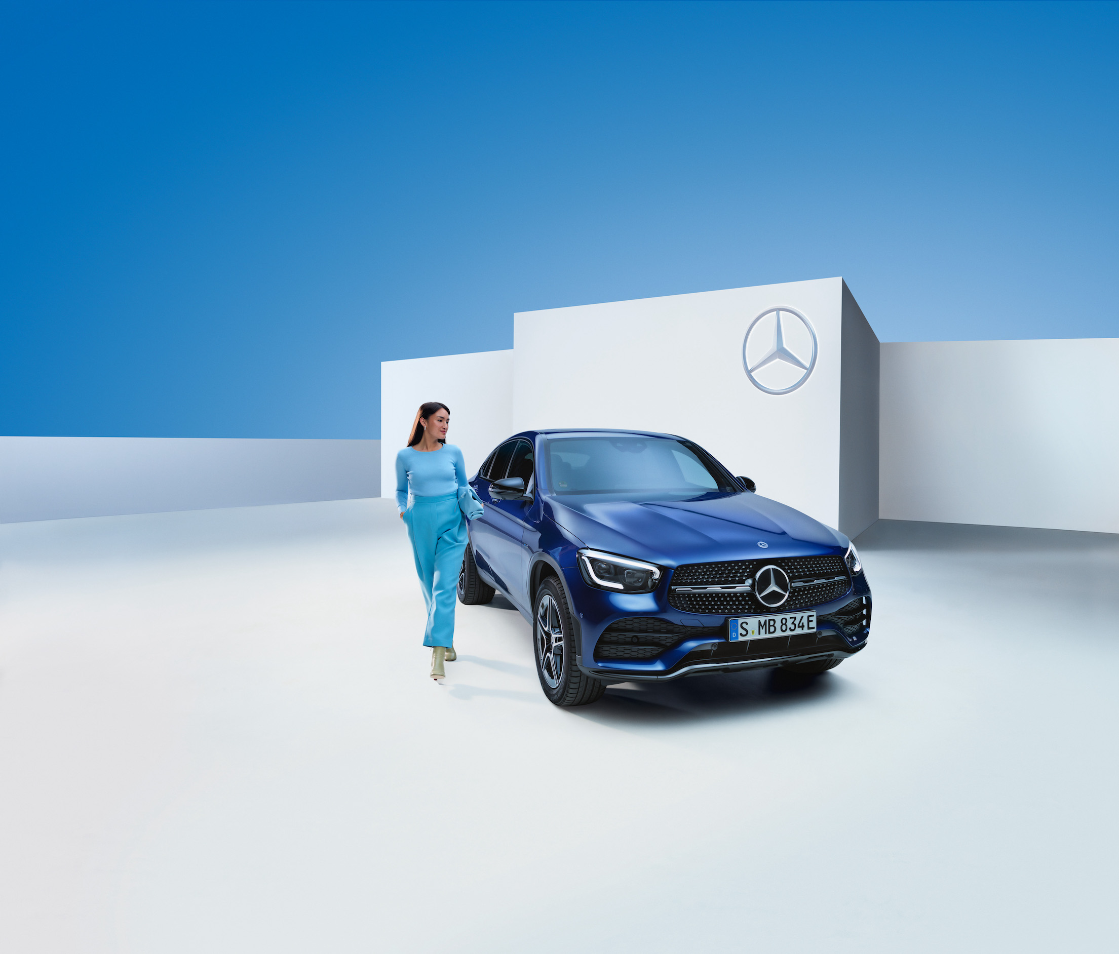 Mercedes-Benz | Originální prostředky pro péči Žena stojí vedle svého vozu Mercedes-Benz.