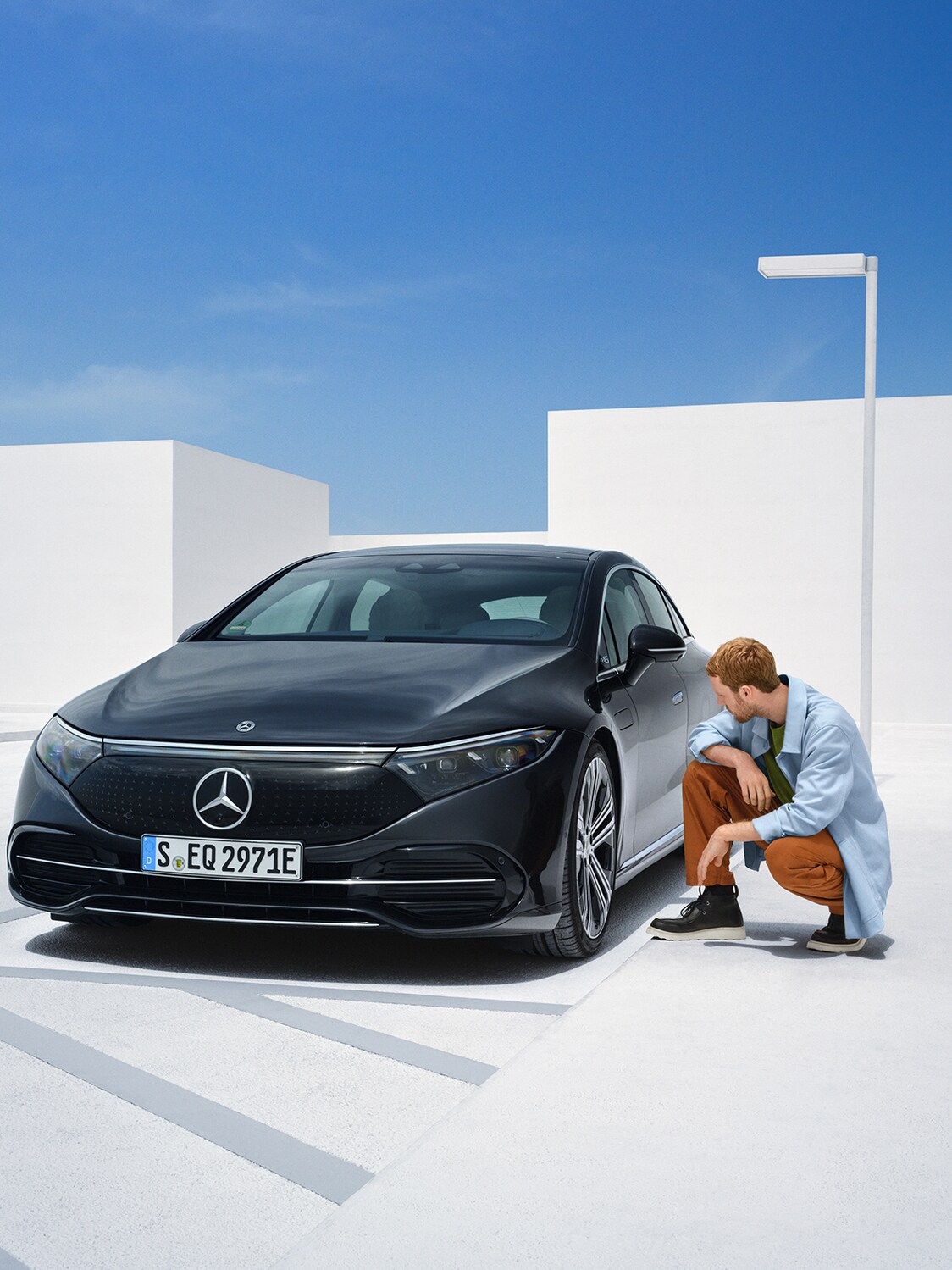 Osoba klečí u&nbsp;svého vozidla Mercedes-Benz, aby ho zkontrolovala.