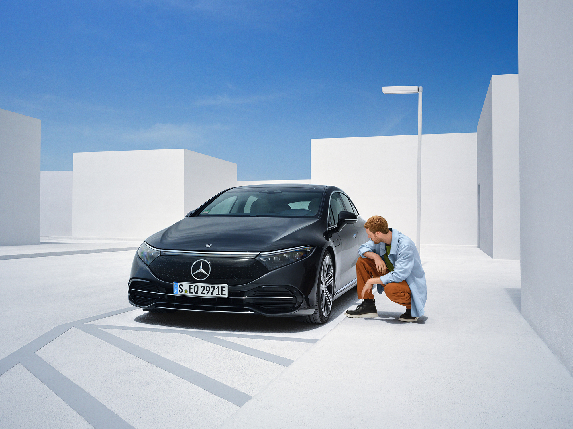 Poškození při nehodě | Mercedes-Benz Osoba klečí u svého vozidla Mercedes-Benz, aby ho zkontrolovala.