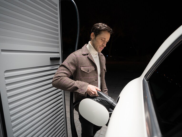 Muž nabíjející svůj elektromobil Mercedes-Benz na nabíjecí stanici.