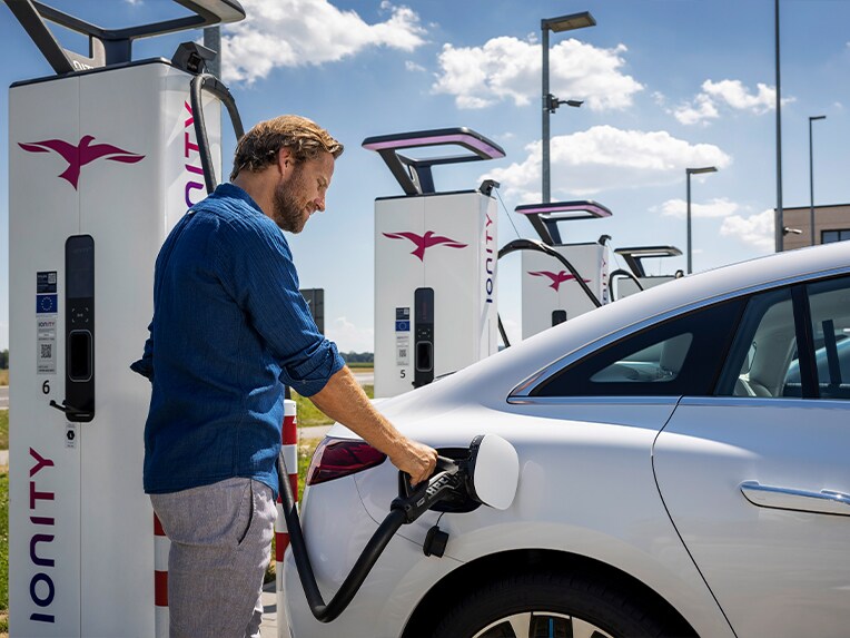 Muž nabíjející svůj vůz Mercedes-Benz EQS na nabíjecí stanici IONITY Unlimited.