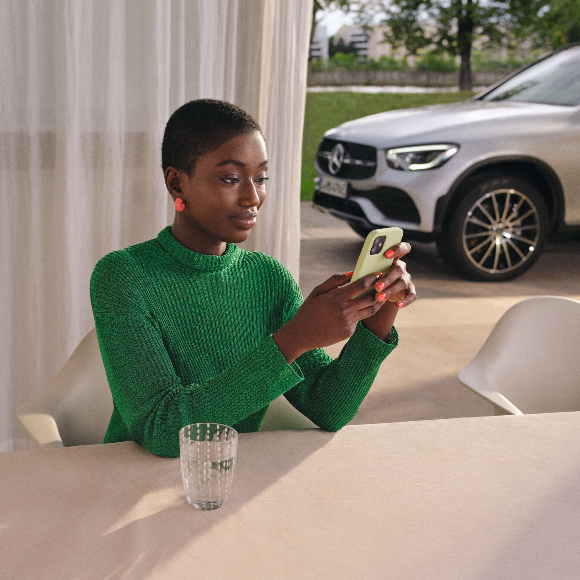 Vzdálená diagnostika | Standardní služby | Mercedes-Benz Žena kontroluje pomocí chytrého telefonu stav svého vozidla.