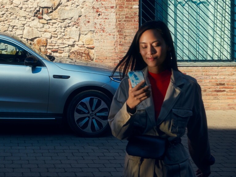 Žena používá aplikaci Mercedes-Benz na svém chytrém telefonu k propojení se svým vozem Mercedes-Benz.