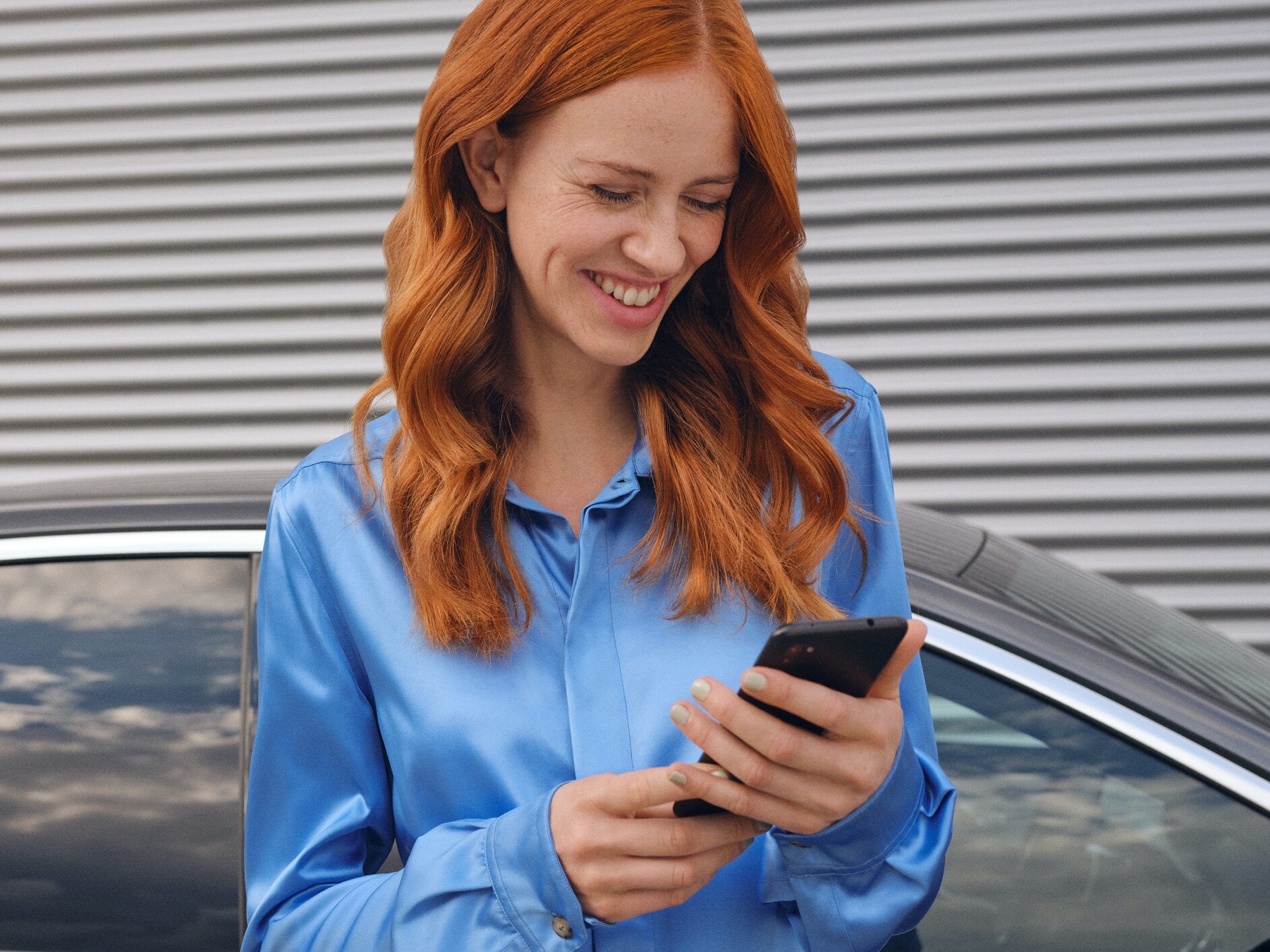 Žena vytváří přes aplikaci Mercedes me na svém chytrém telefonu spojení se svým vozidlem Mercedes-Benz.