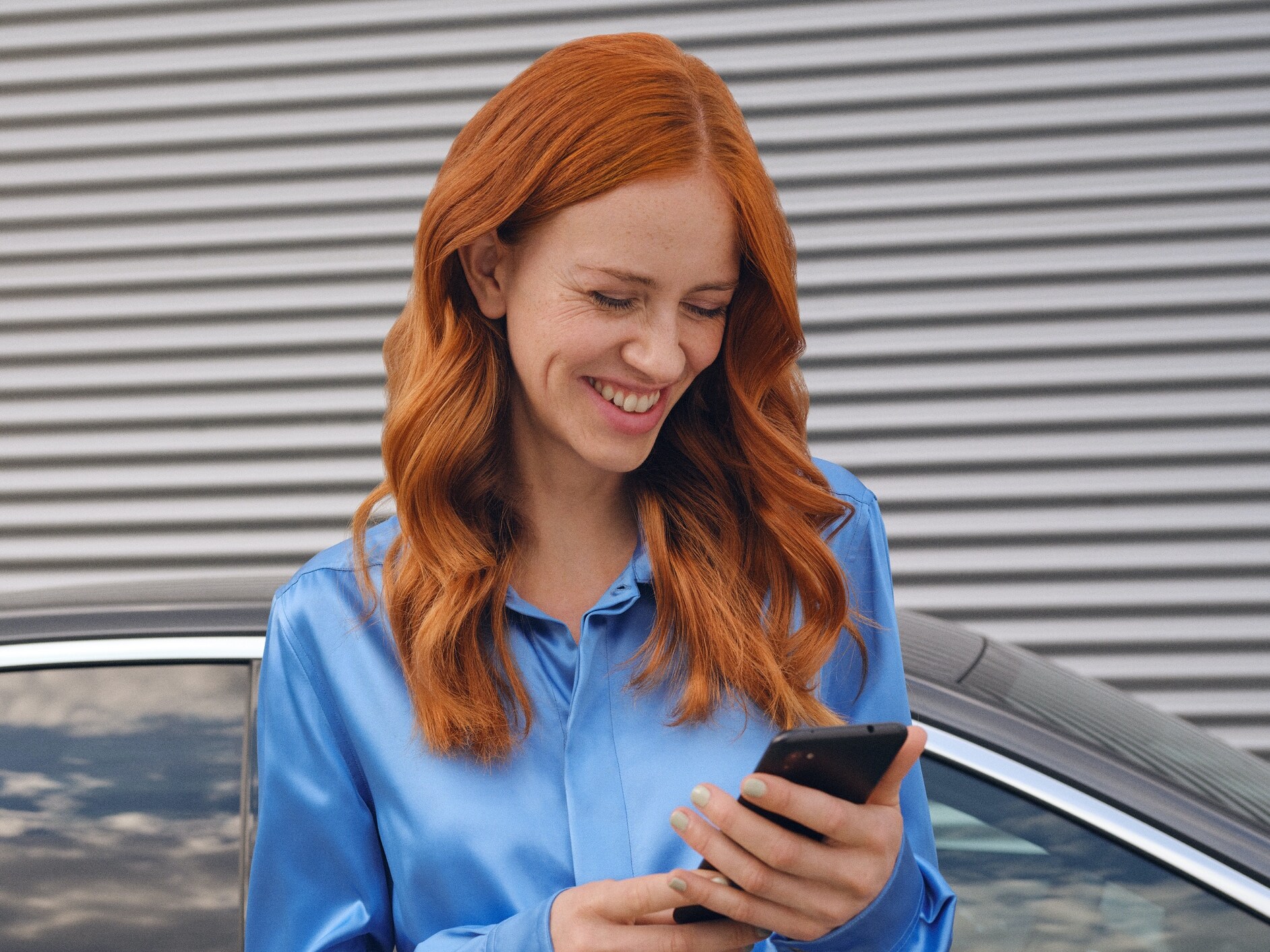 Žena tvoří přes aplikaci Mercedes-Benz na svém telefonu spojení se svým vozidlem.