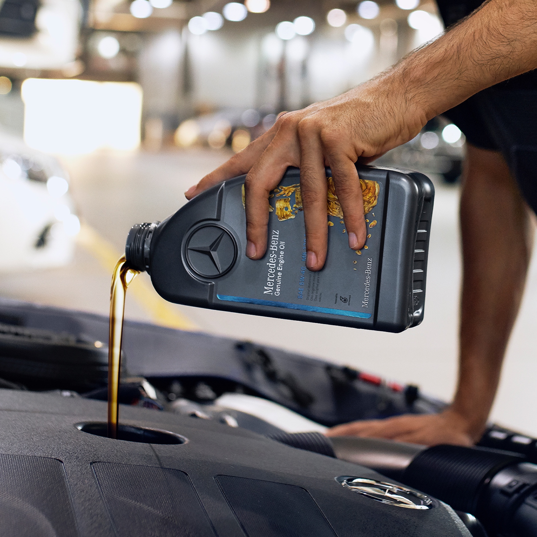 Motorový olej | Mercedes-Benz Osoba, která nalévá motorový olej do vozu Mercedes-Benz.