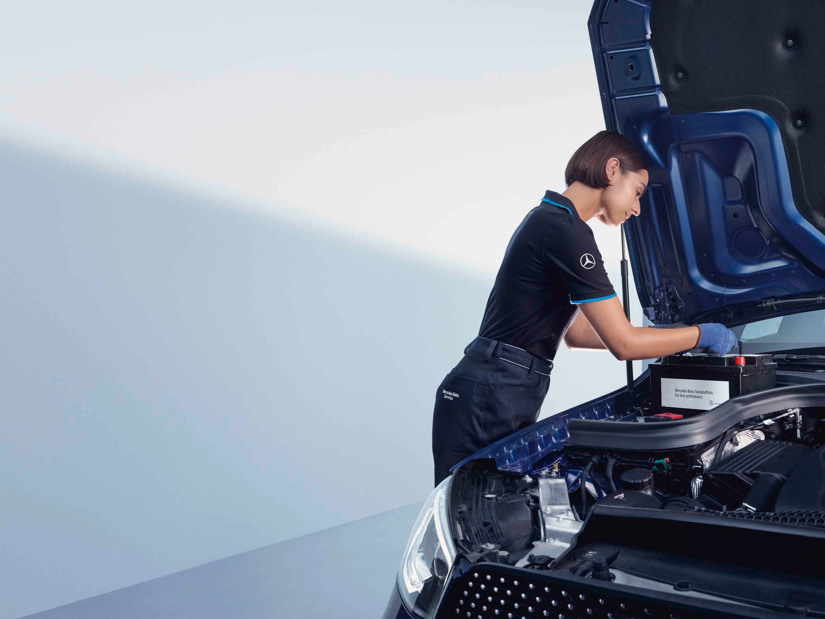 Automechanik se sklání nad otevřenou kapotou vozu Mercedes-Benz.
