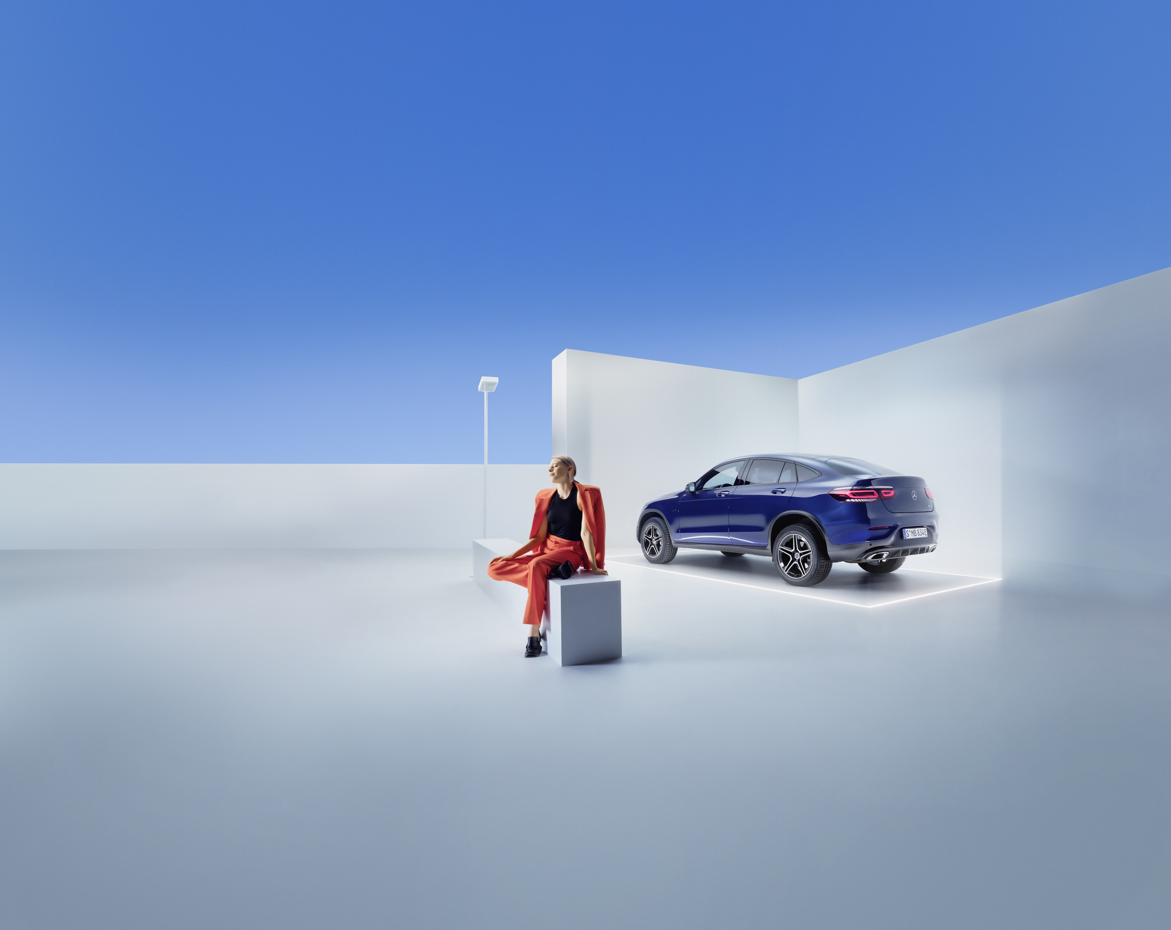 Servisní smlouvy Mercedes-Benz Žena sedí na lavici před vozem Mercedes-Benz.