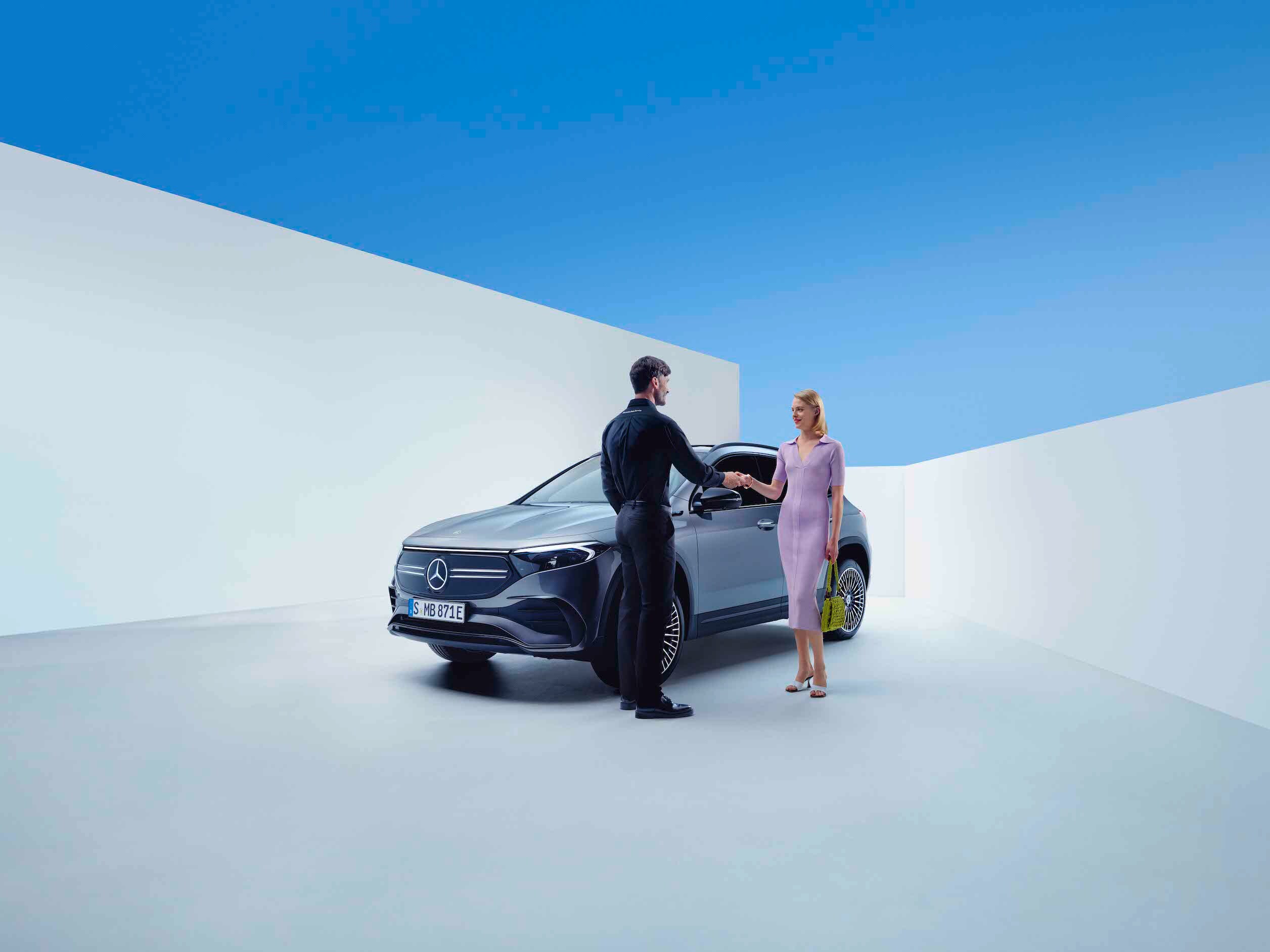 Muž a žena si podávají za ruku před vozidlem Mercedes-Benz.