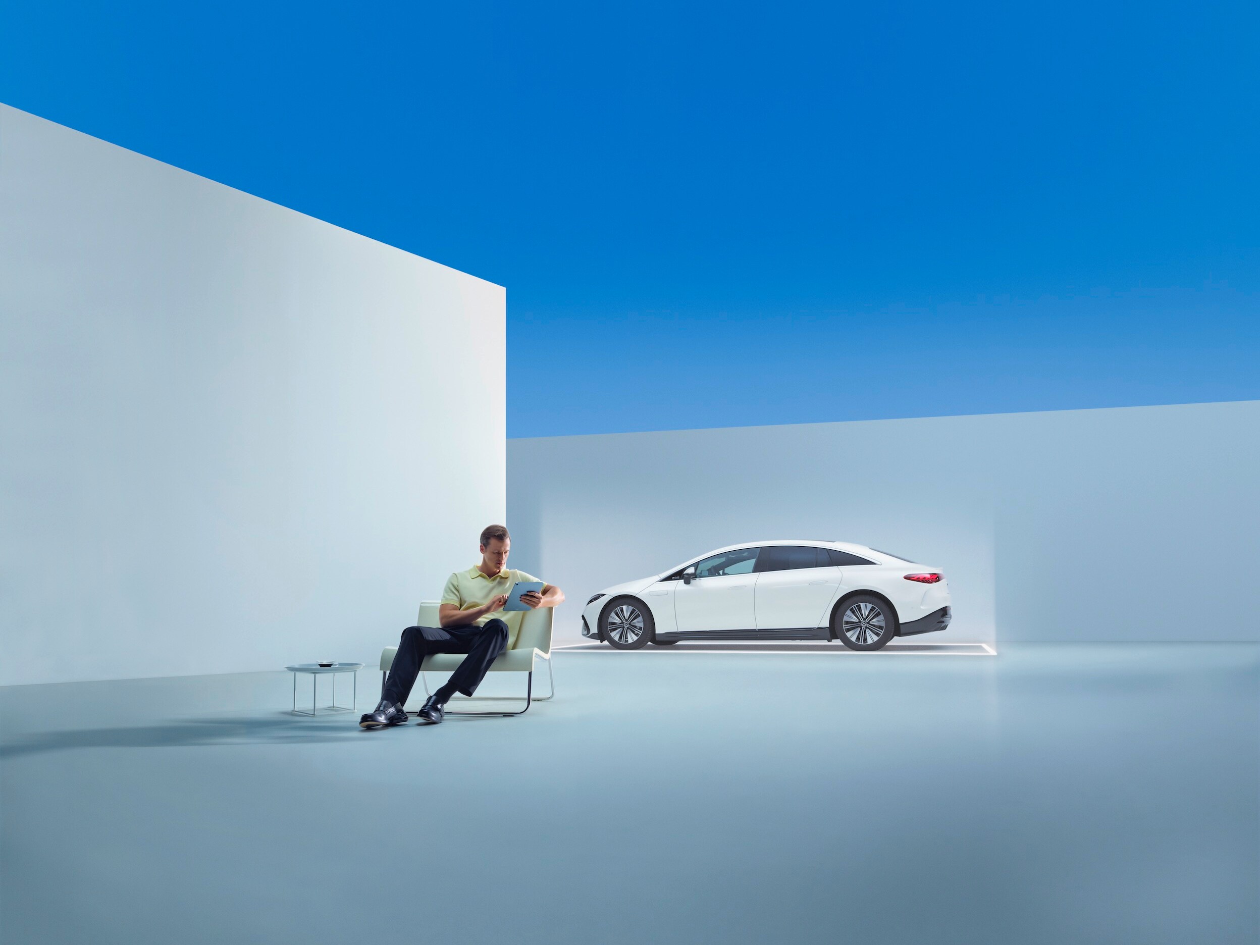 Muž relaxuje v křesle před vozem Mercedes-Benz.