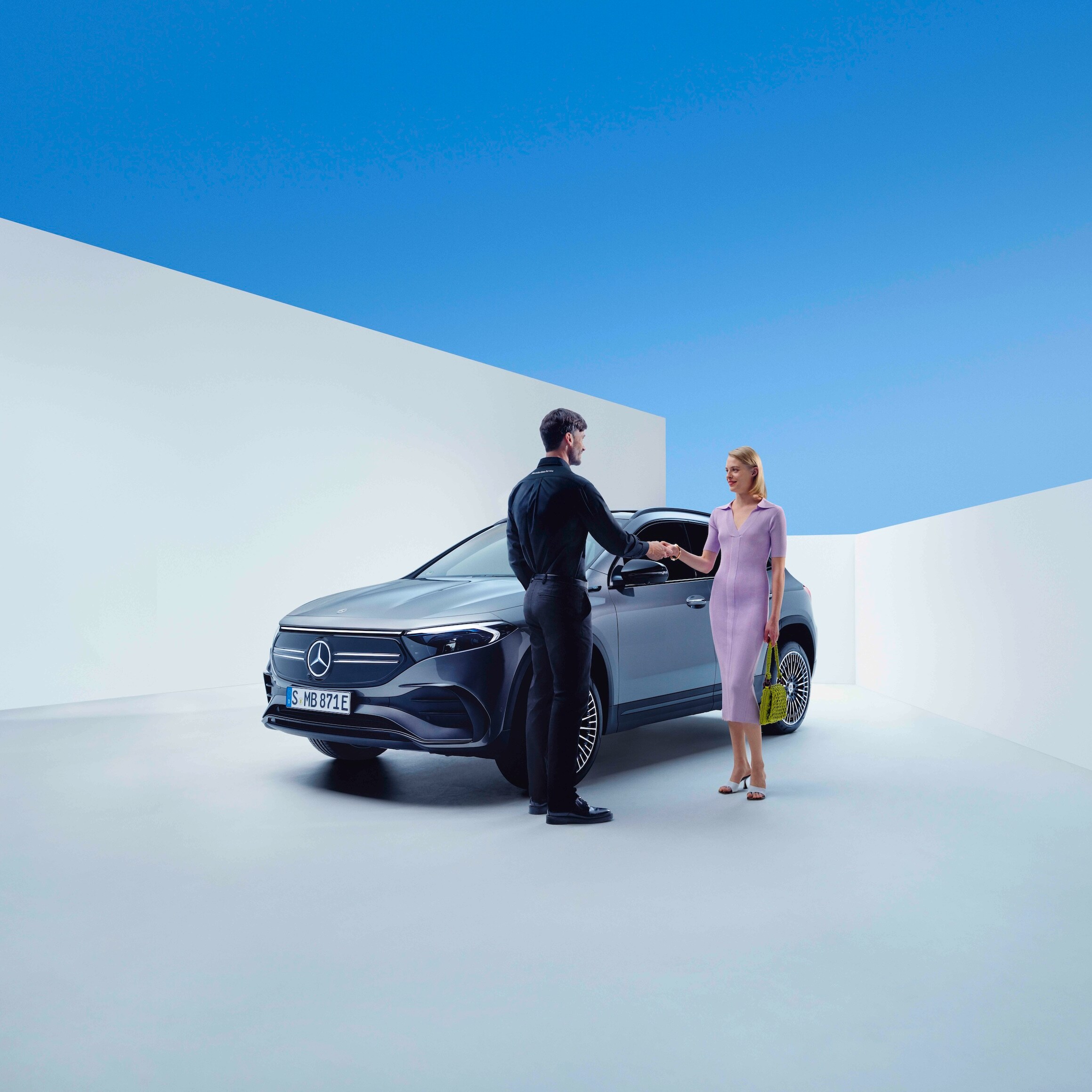 Zaměstnanec Mercedes-Benz a&nbsp;žena si podávají ruce před vozidlem Mercedes-Benz
