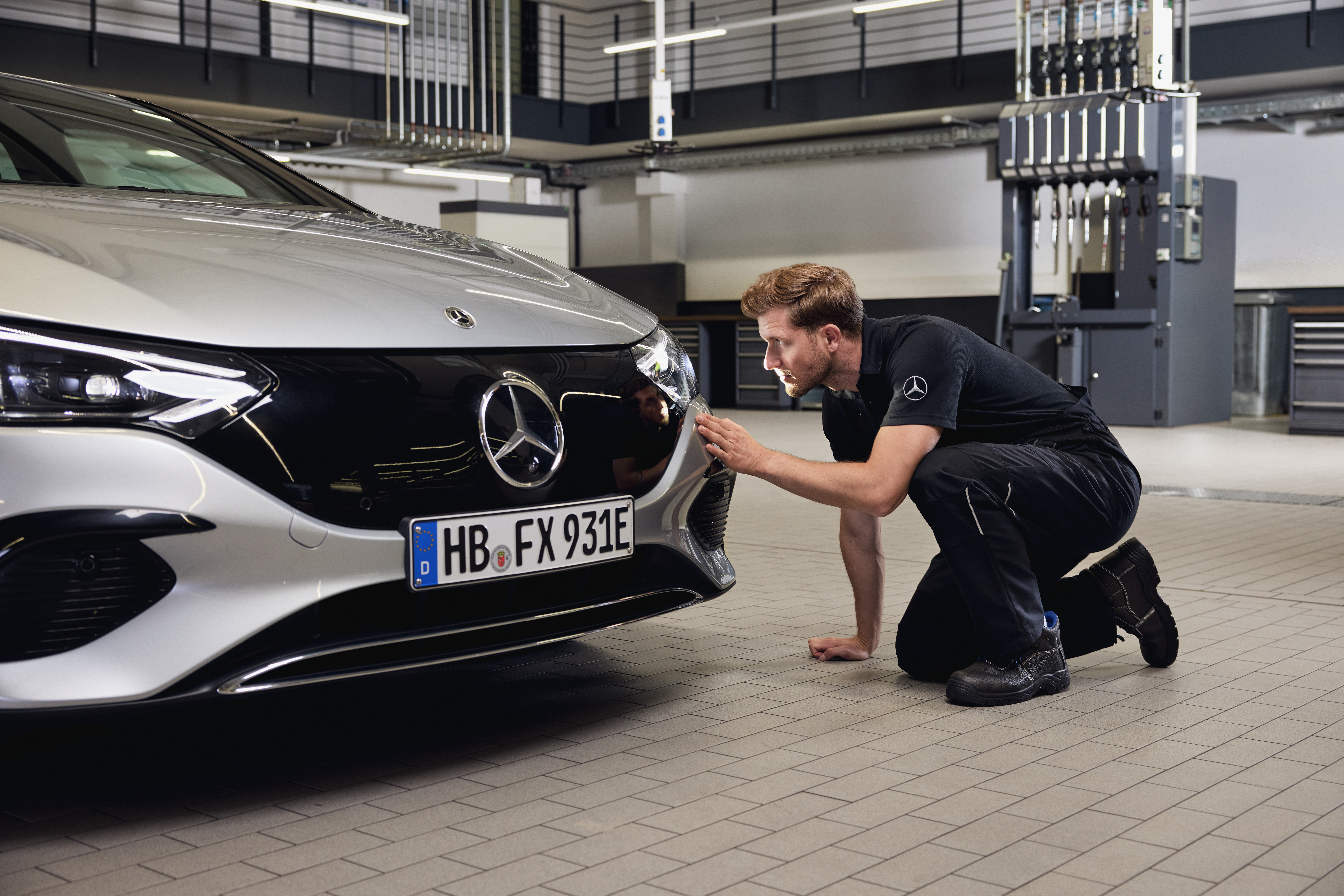 Výměna originálních světlometů Mercedes-Benz Detailní pohled na příď vozidla Mercedes-Benz s technikem provádějícím podrobnou kontrolu při výměně originálních dílů Mercedes-Benz.