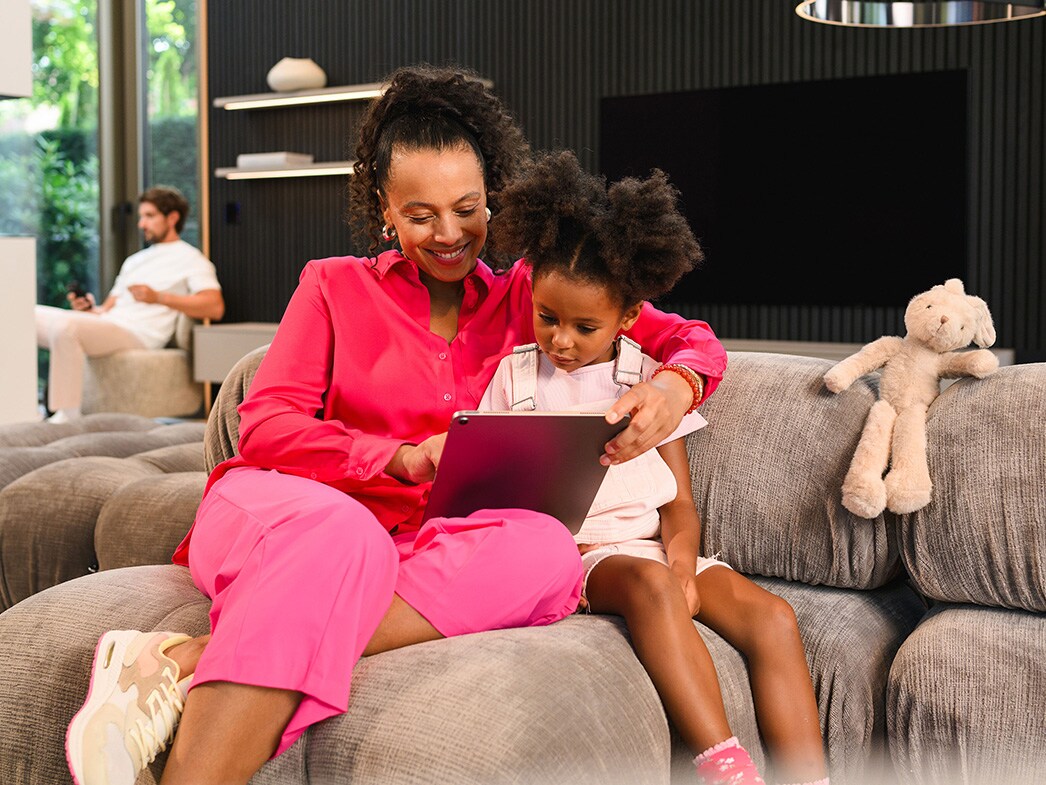 Žena s&nbsp;dítětem sedící na pohovce se dívají do tabletu.
