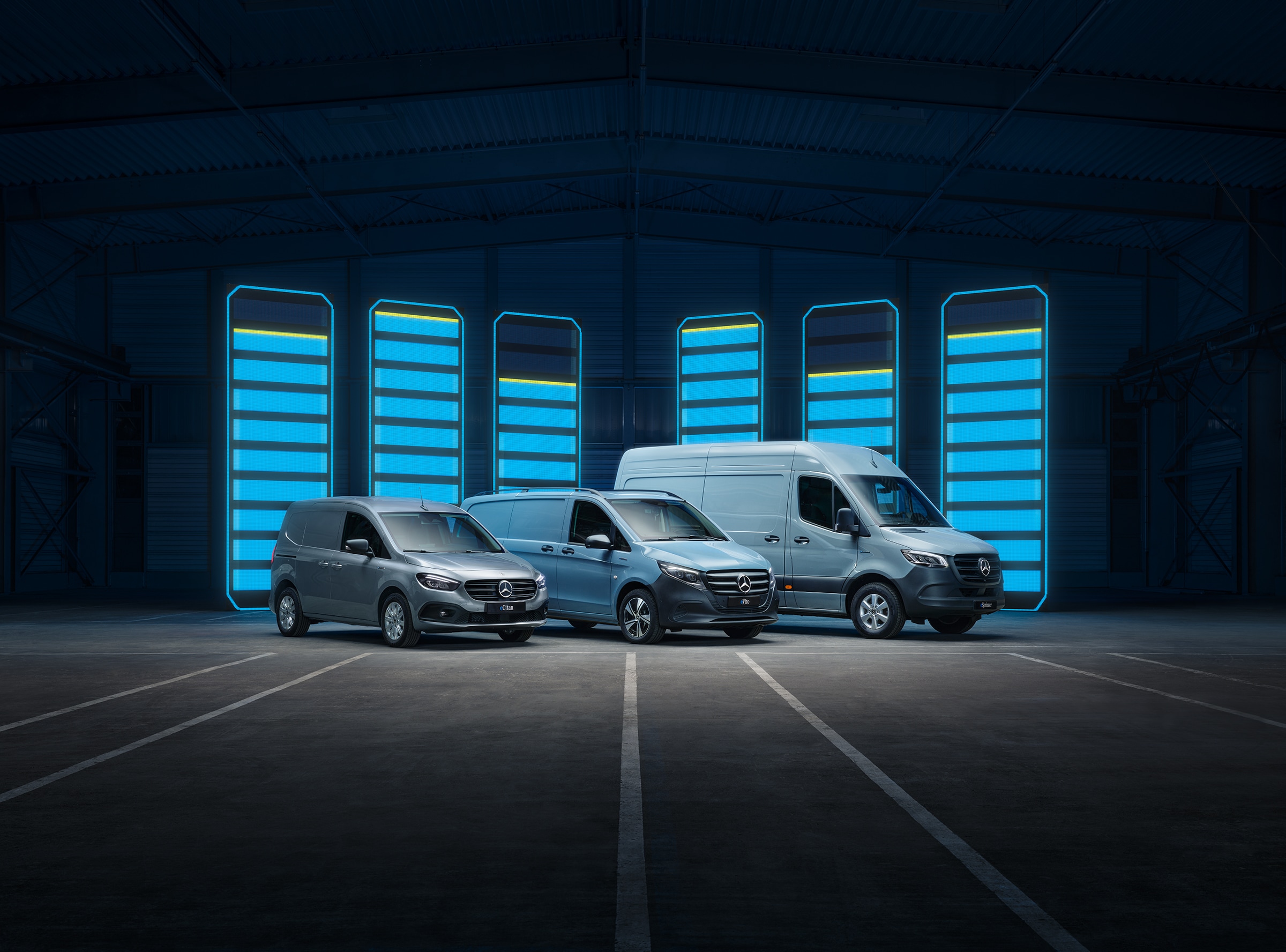 Modelová řada elektrických dodávkových vozidel Mercedes-Benz | Historie užitkových vozidel | Mercedes-Benz Modelová řada elektrických dodávkových vozidel Mercedes-Benz vystavená ve futuristickém skladu s osvětlenými nabíjecími lištami