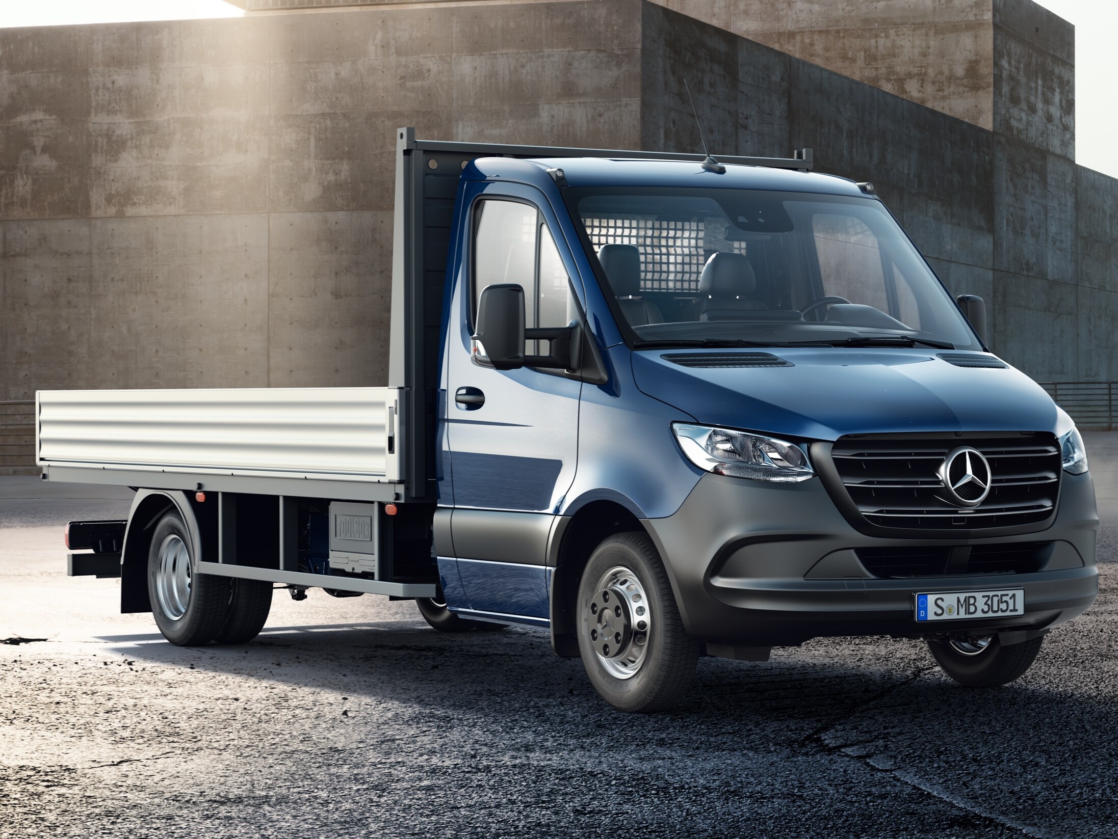Valníkové vozidlo Sprinter od Mercedes-Benz stojí se zvednutým valníkem uprostřed staveniště.