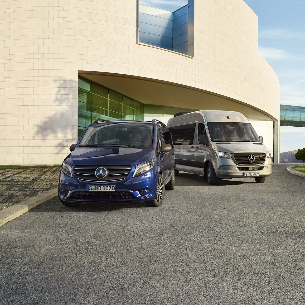 Mercedes-Benz Vito Tourer a&nbsp;Sprinter Tourer před moderním domem.