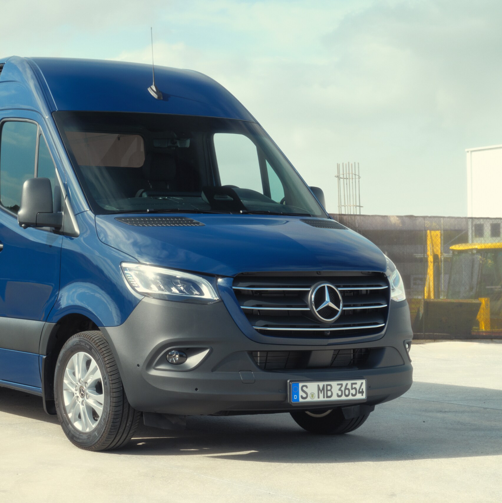 Skříňová dodávka Mercedes-Benz Sprinter před stavebním materiálem.