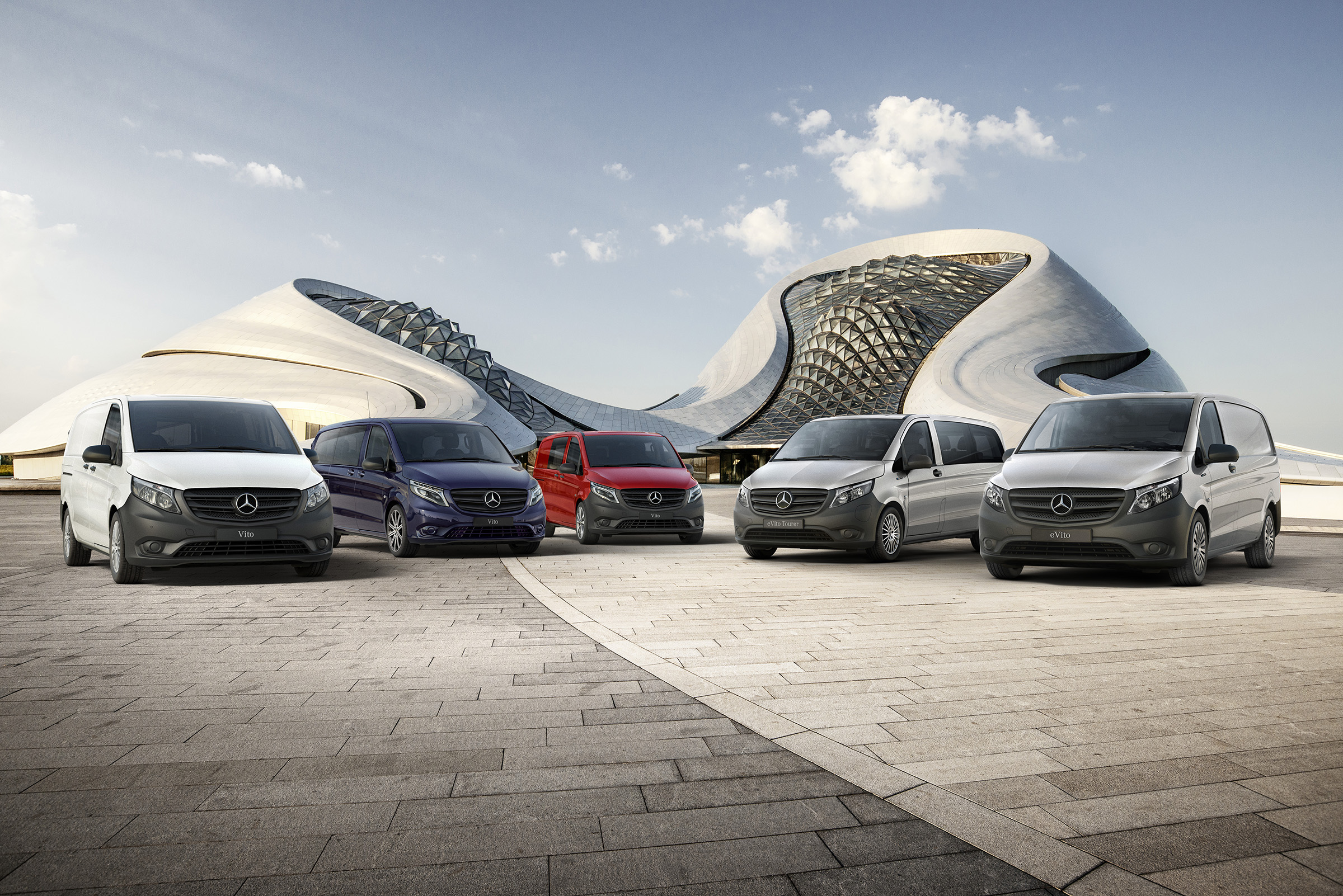 Dojezd modelu Vito | Všechny modely Vito | Dodávková vozidla Mercedes-Benz Vozidla Mercedes-Benz eVito skříňová dodávka, Vito skříňová dodávka, Vito Mixto, eVito Tourer a Vito Tourer stojí vedle sebe před futuristickou budovou