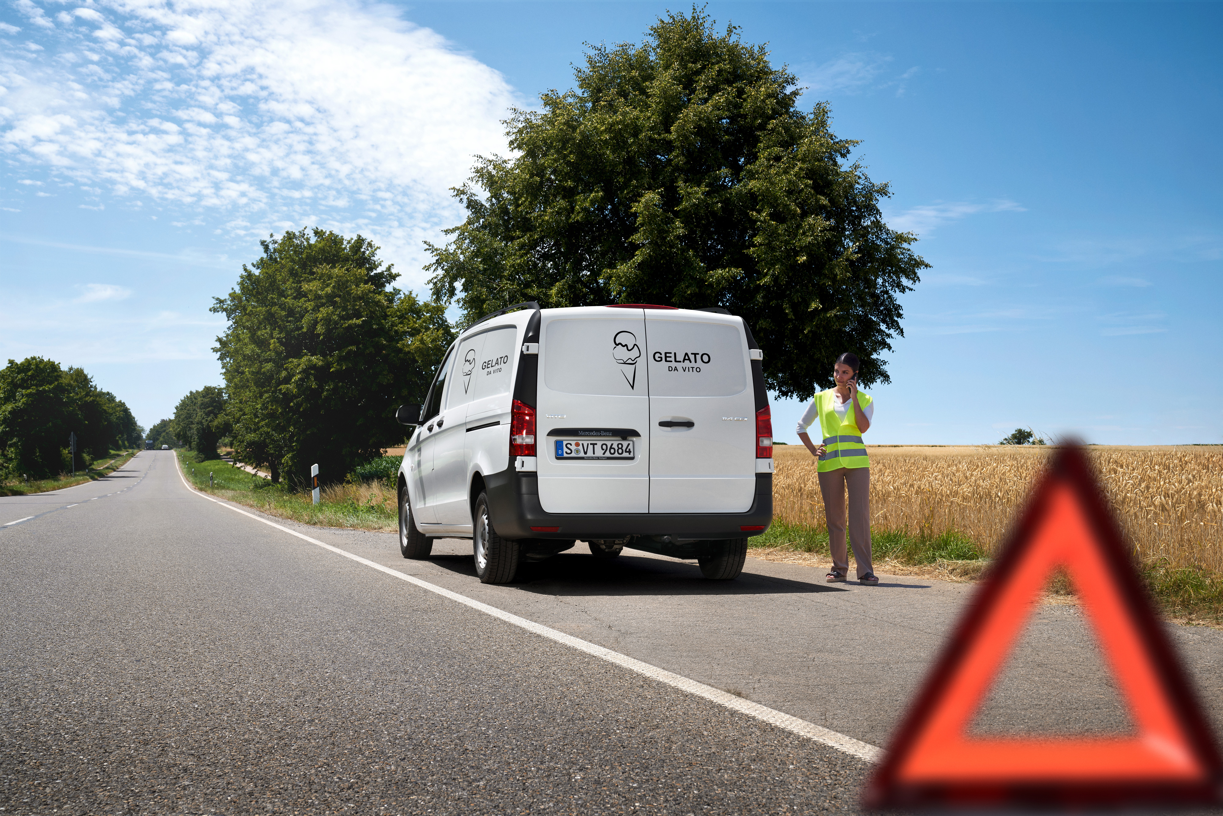 Mercedes-Benz | Péče o dodávky | Service24h Žena volá na servisní hotline Mercedes-Benz Service24h, u krajnice venkovské silnice stojí dodávka Mercedes-Benz Sprinter.