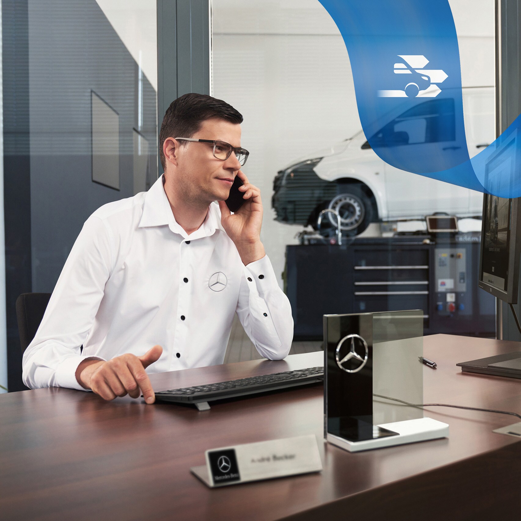 Zaměstnanec sedí u stolu a telefonuje, v pozadí dodávkové vozidlo Mercedes-Benz Vito v dílně.