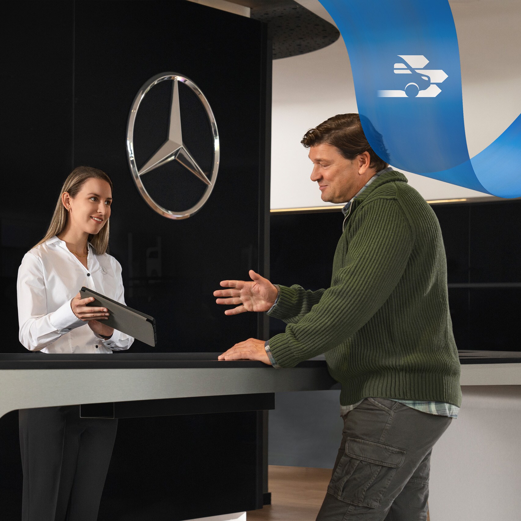 Zaměstnanec společnosti Mercedes-Benz poskytuje zákazníkovi podporu, přičemž stojí na recepci.