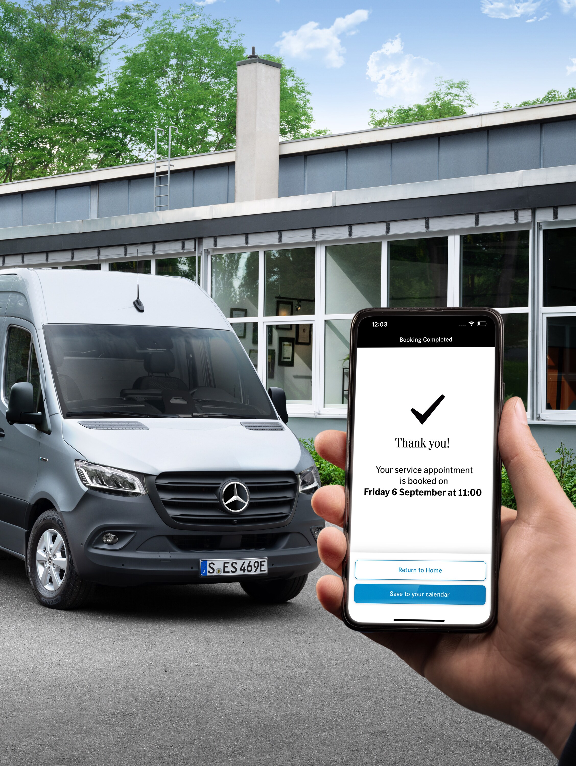 Šedé dodávkové vozidlo Mercedes-Benz Sprinter před kanceláří s&nbsp;osobou držící chytrý telefon v&nbsp;popředí.