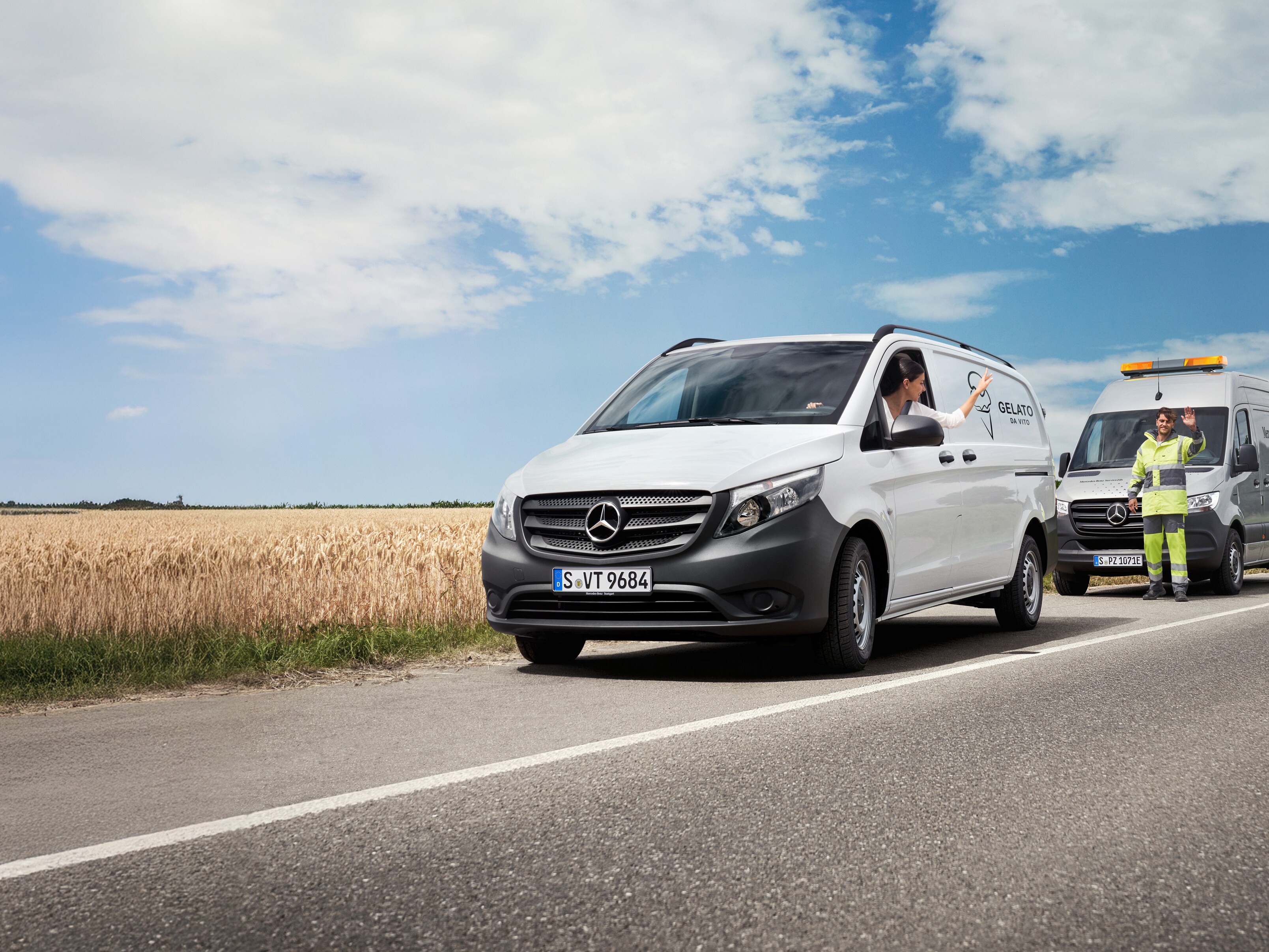 Žena sedící v&nbsp;bílém vozidle Mercedes-Benz Vito mává servisnímu technikovi Mercedes-Benz na kraji silnice.