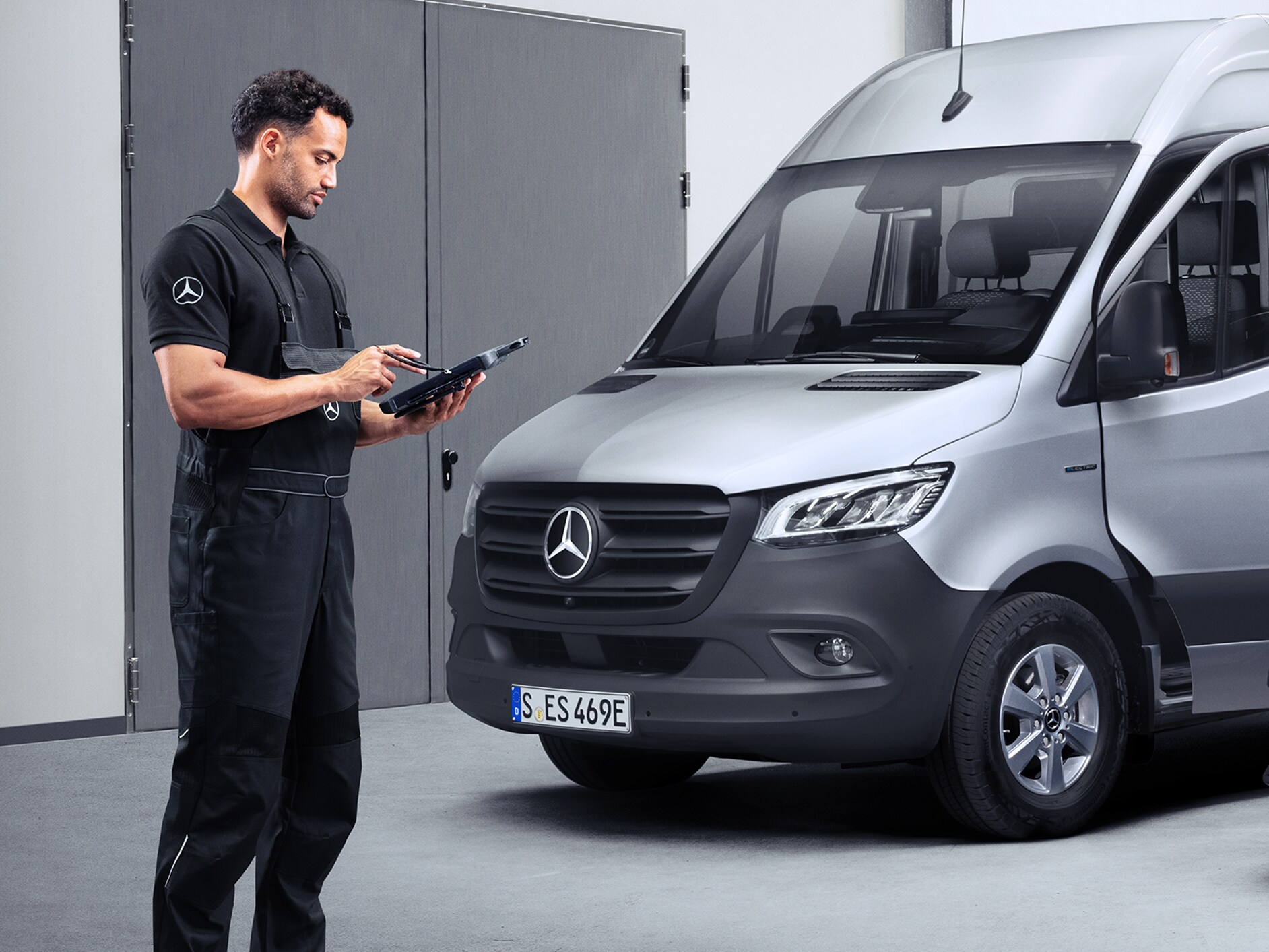 Servisní partner Mercedes-Benz s tabletem, který stojí před vozidlem Mercedes-Benz eSprinter.