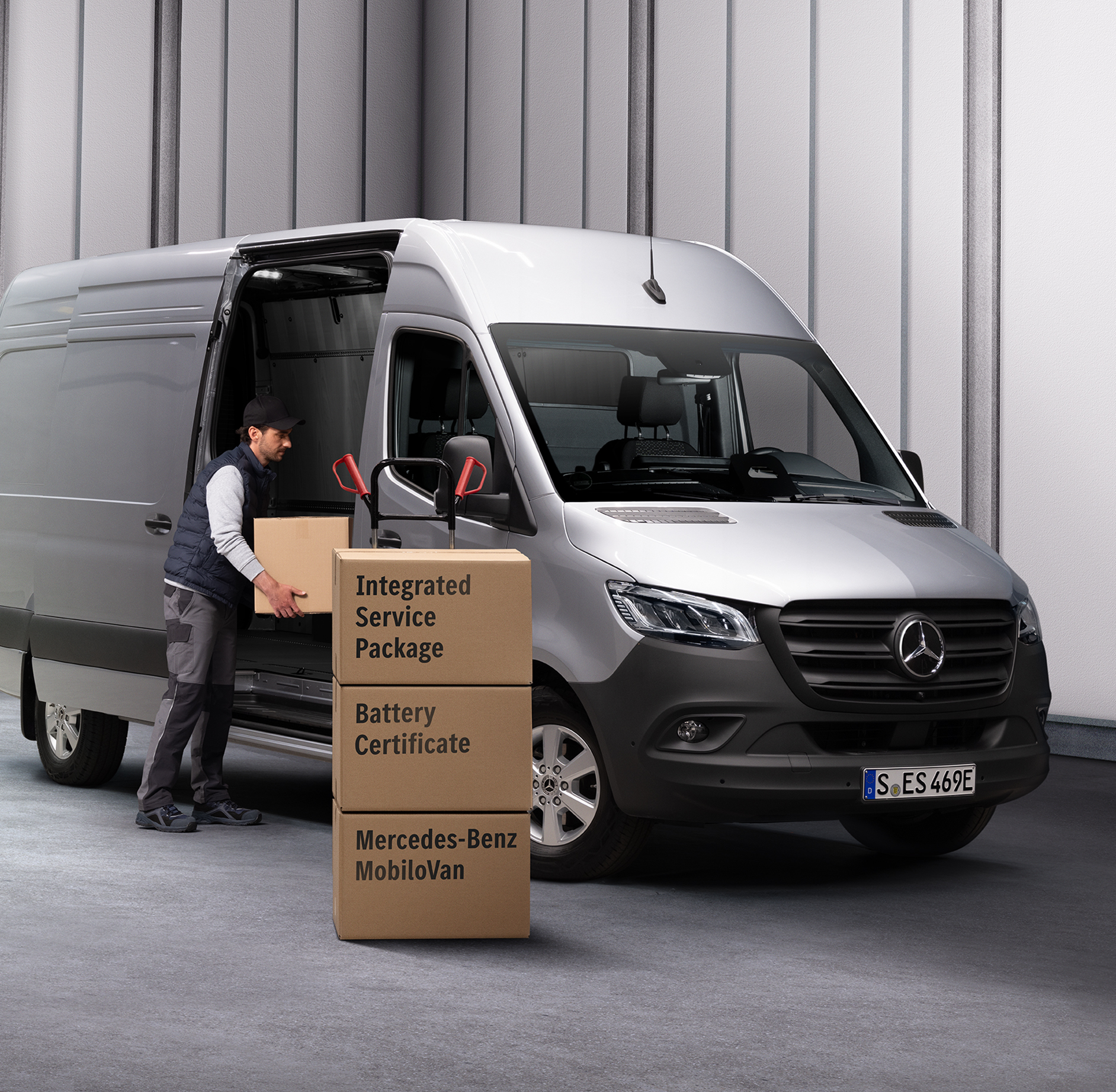 Servisní partner Mercedes-Benz | Integrovaná smlouva Maintenance Osoba vykládající krabice z vozidla Mercedes-Benz eSprinter. Před dodávkovým vozidlem jsou naskládány tři krabice. Krabice jsou označeny názvy servisních produktů Mercedes-Benz.