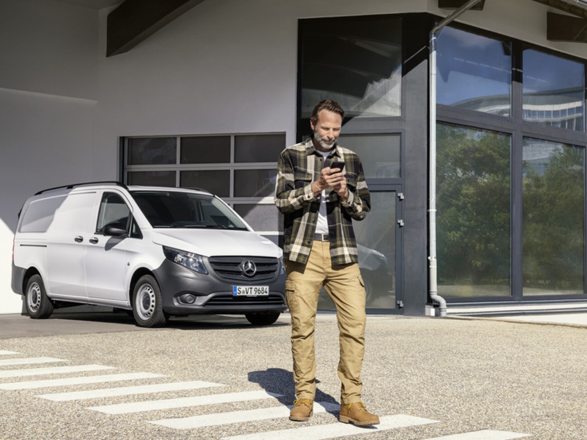 Osoba s&nbsp;chytrým telefonem před vozidlem Mercedes-Benz Vito.