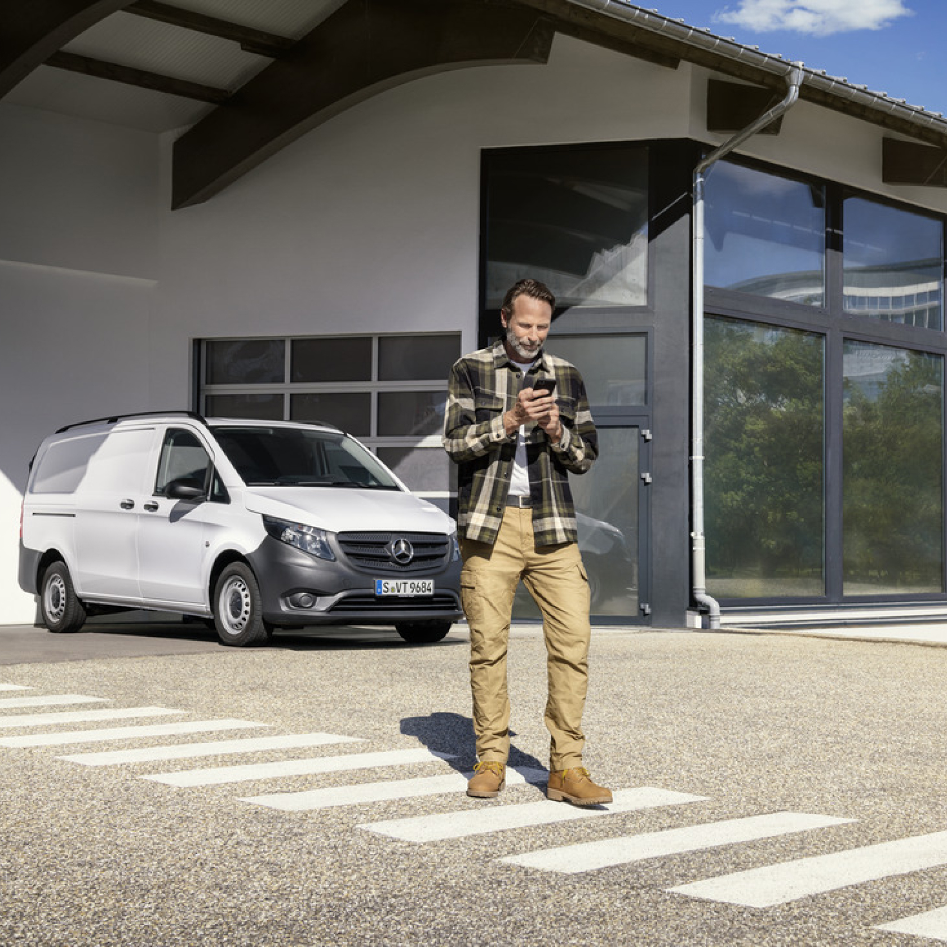 Mercedes-Benz Store | Digitální doplněk | Mercedes-Benz Osoba s chytrým telefonem před vozidlem Mercedes-Benz Vito.