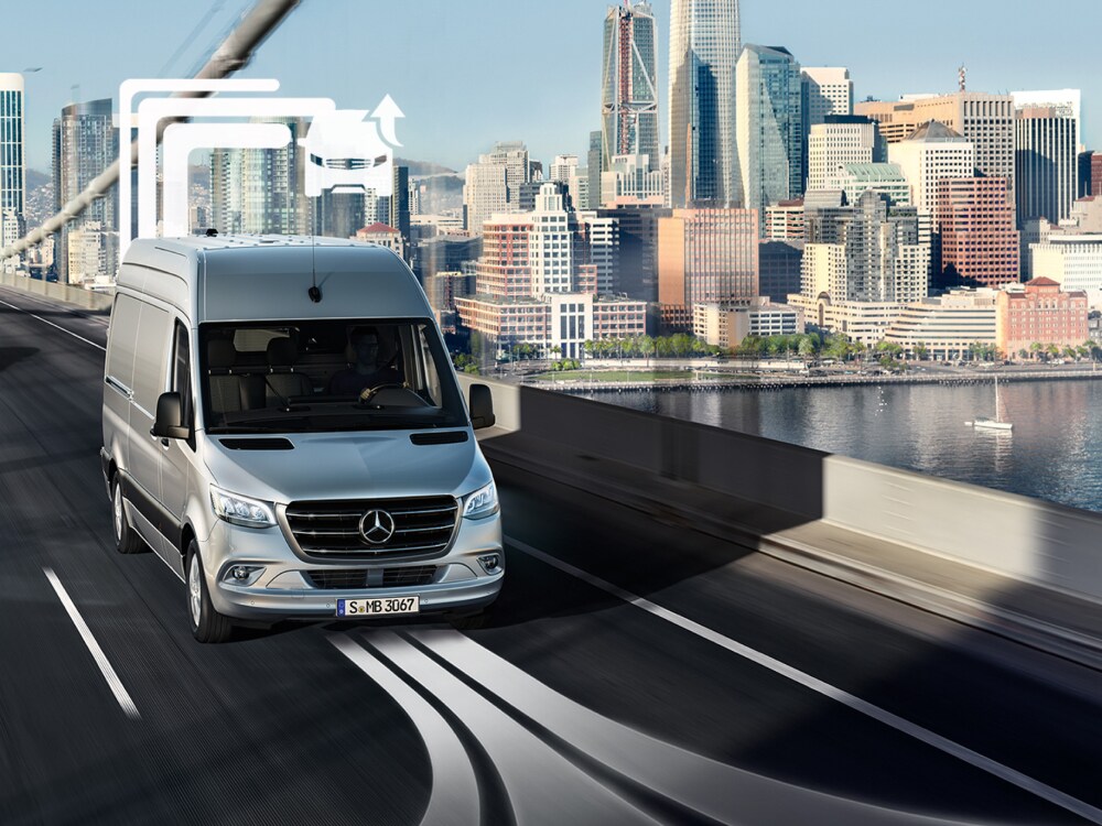 Dodávkové vozidlo Mercedes-Benz ve dne přejíždí přes most s více jízdními pruhy.