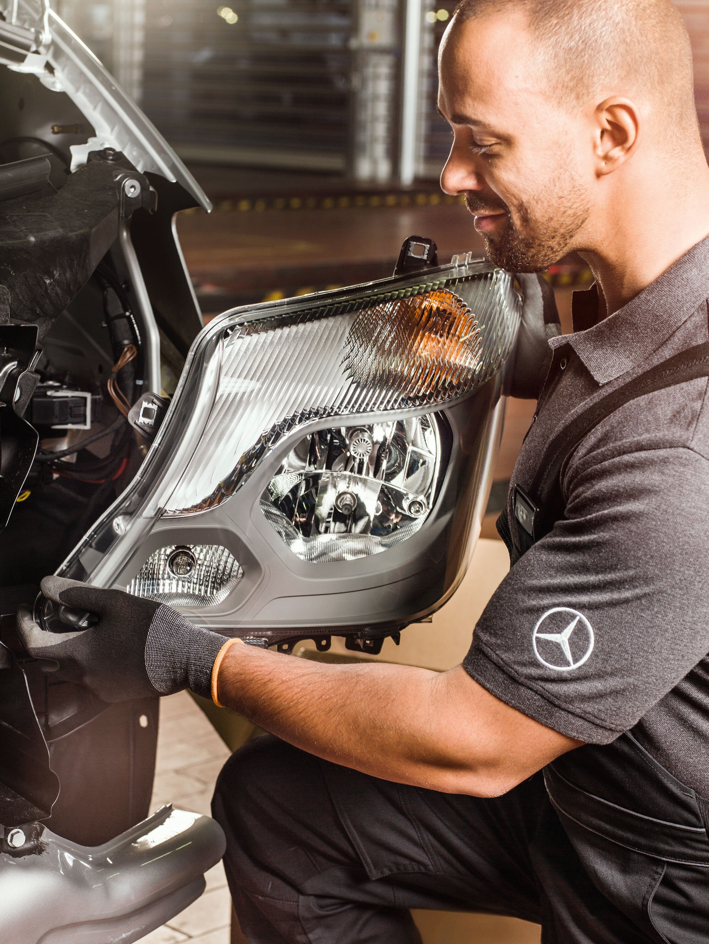 Mechanik kontroluje originální díly Mercedes-Benz před otevřeným motorem vozidla Sprinter a&nbsp;porovnává je s&nbsp;katalogem náhradních dílů Mercedes.